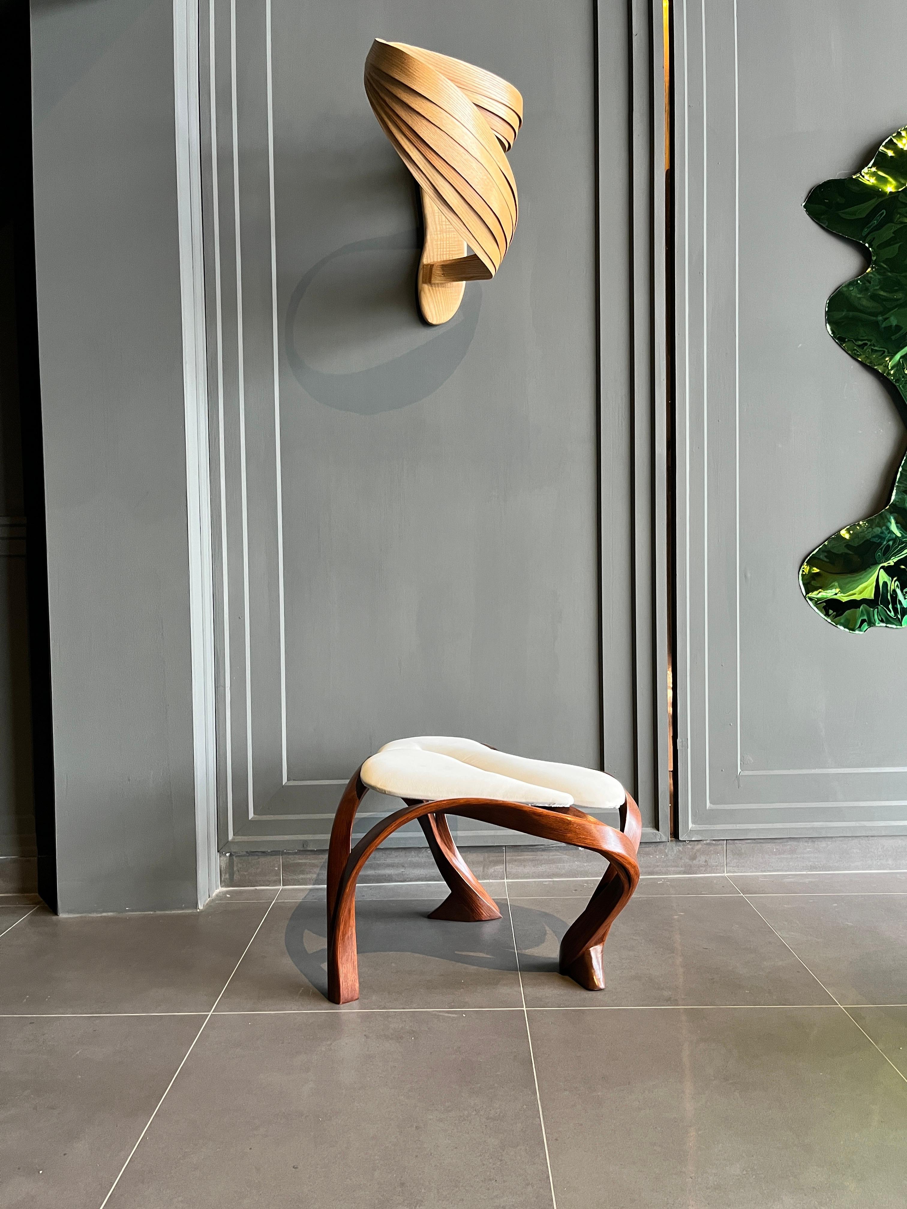 The stool has a free form design that makes it asymmetrical from all angles. The upholstery has been divided in two sections which allows the fluid frame to flow through the upholstery and also form three legs of the piece. 

Our pieces are based