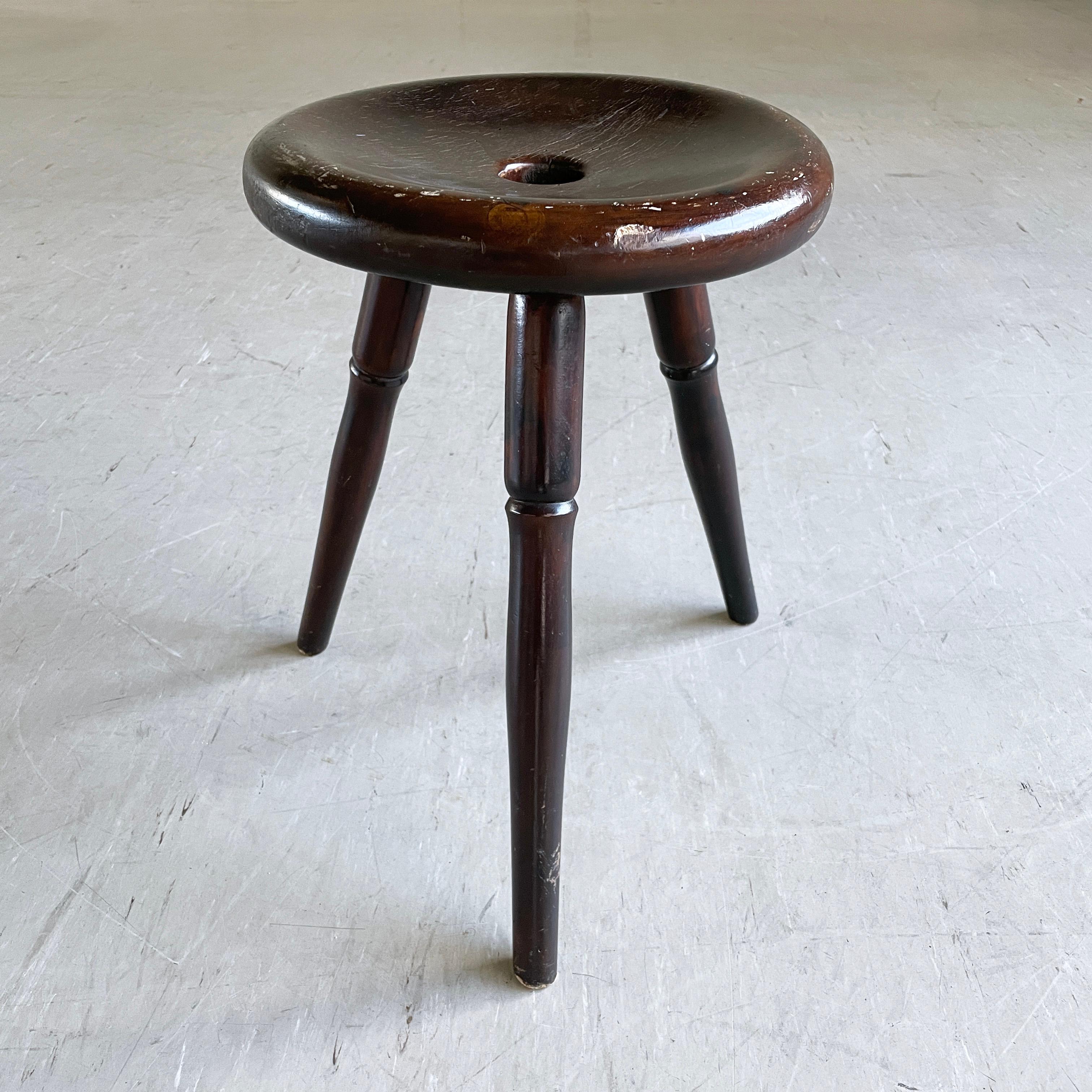Taburete Trípode Vintage Rústico Suizo. Asiento y base de trípode de madera maciza. Con ligera pátina en la madera y leves signos de carcoma (ya desaparecidos). Tiene una estructura totalmente estable y se presta a múltiples usos, como pie de