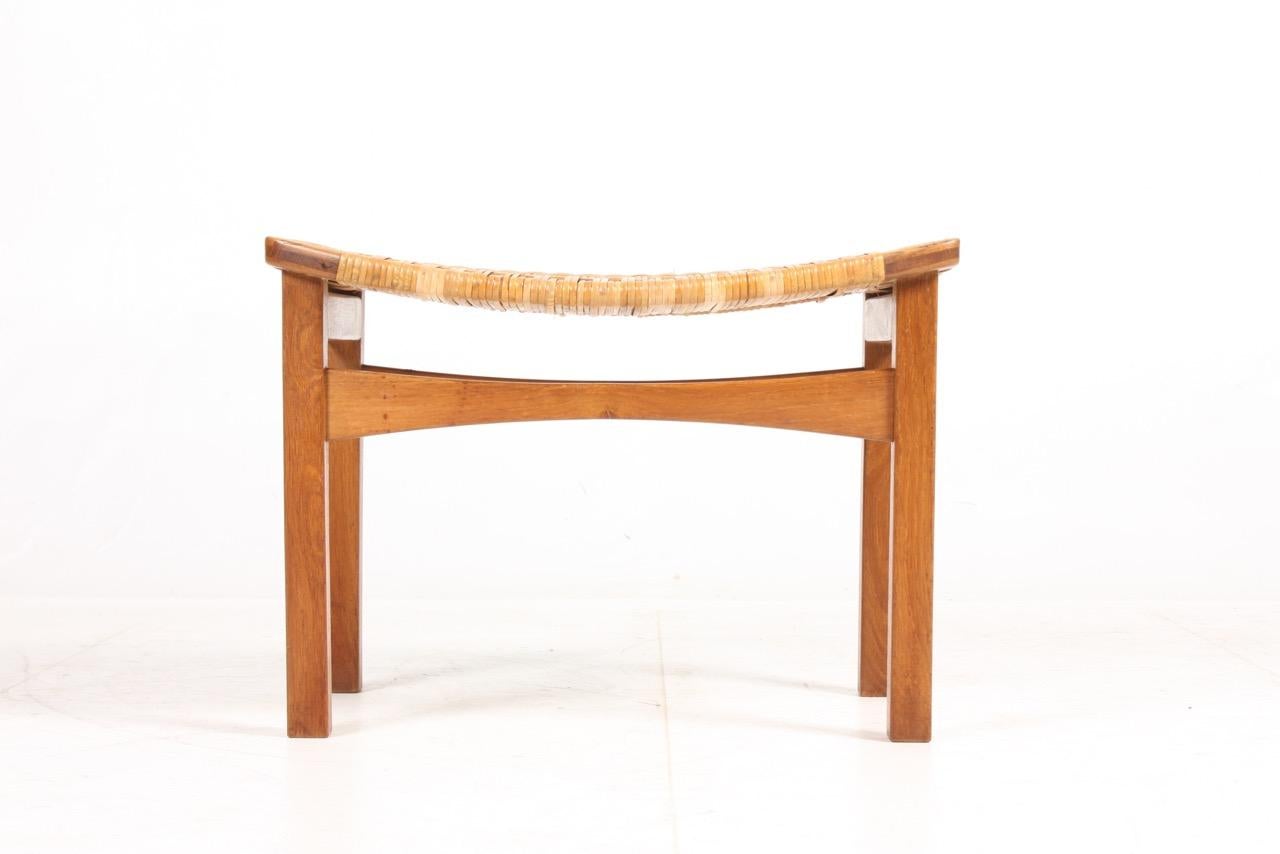 Rare stool in oak and seat in cane, designed by Ejnar Larsen and Aksel Bender Maden for Pontoppidan. Made in Denmark in the 1950s.