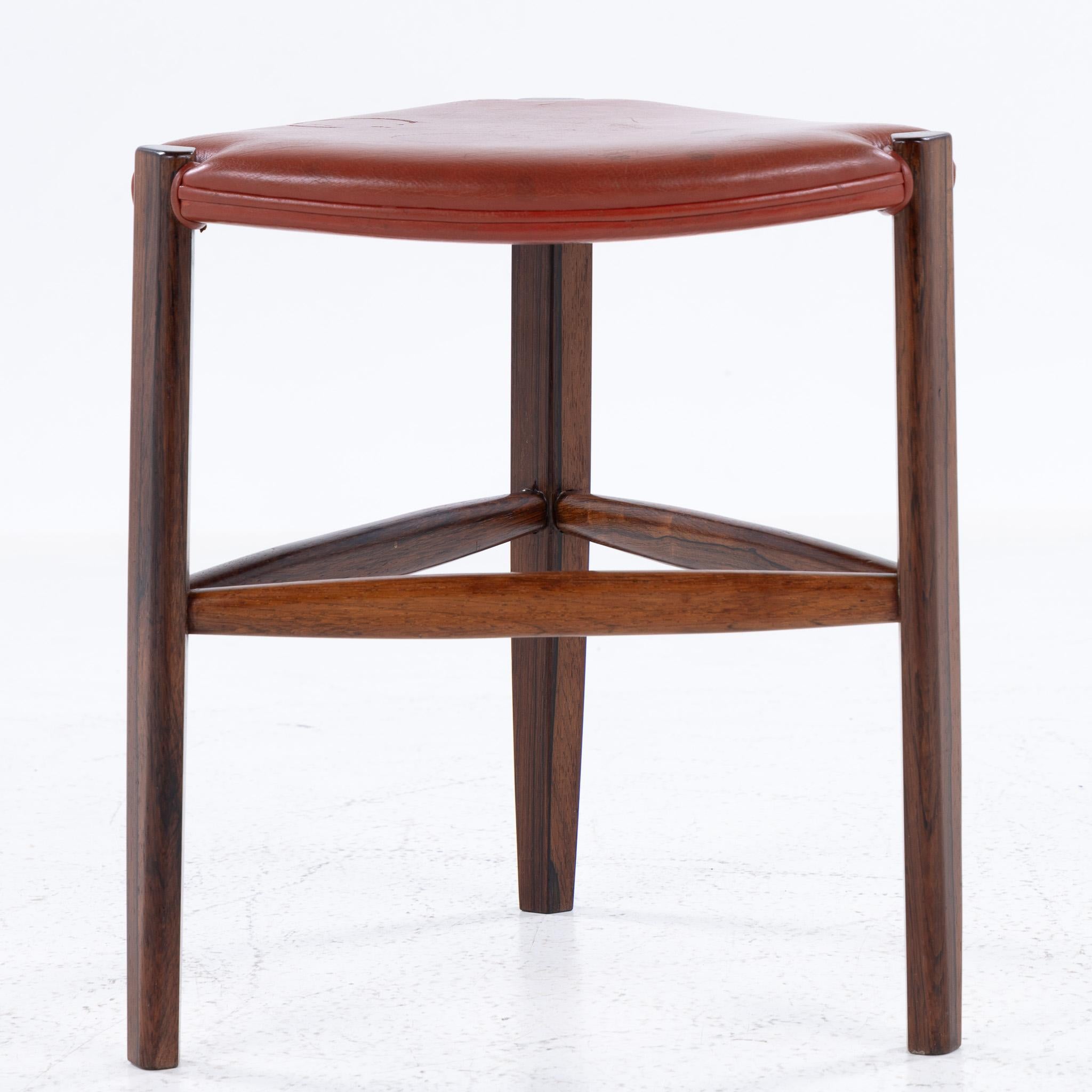 Taburete de tres patas en palisandro y cuero rojo. Diseñado por Tove & Edvard Kindt-Larsen, fabricado por Gustav Bertelsen.