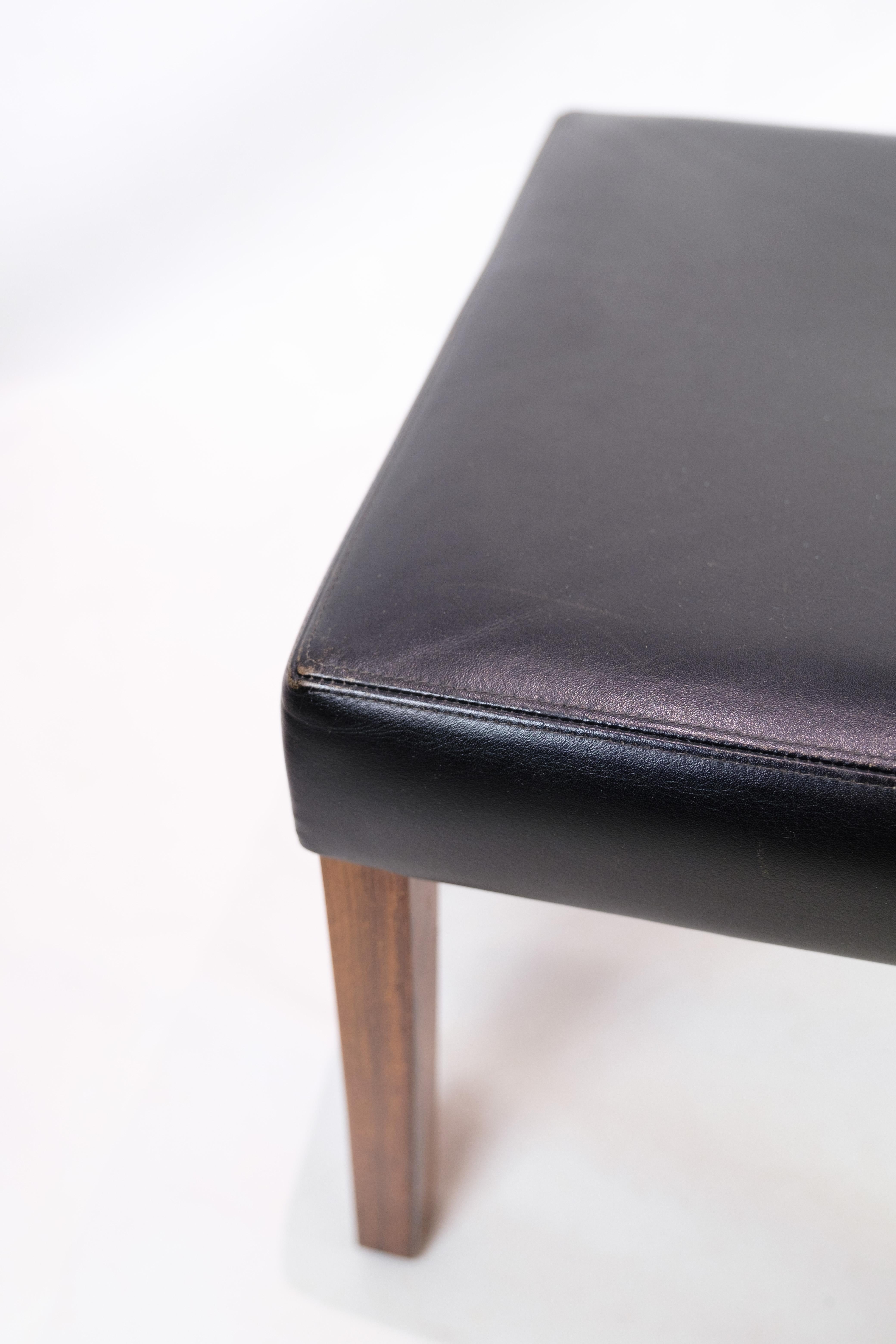 Stool of upholstered black leather with rosewood legs of Danish design produced in the 1960s. The stool appears in very good condition with the original label from the manufacturer, as well as the furniture control sticker. The seating comfort on
