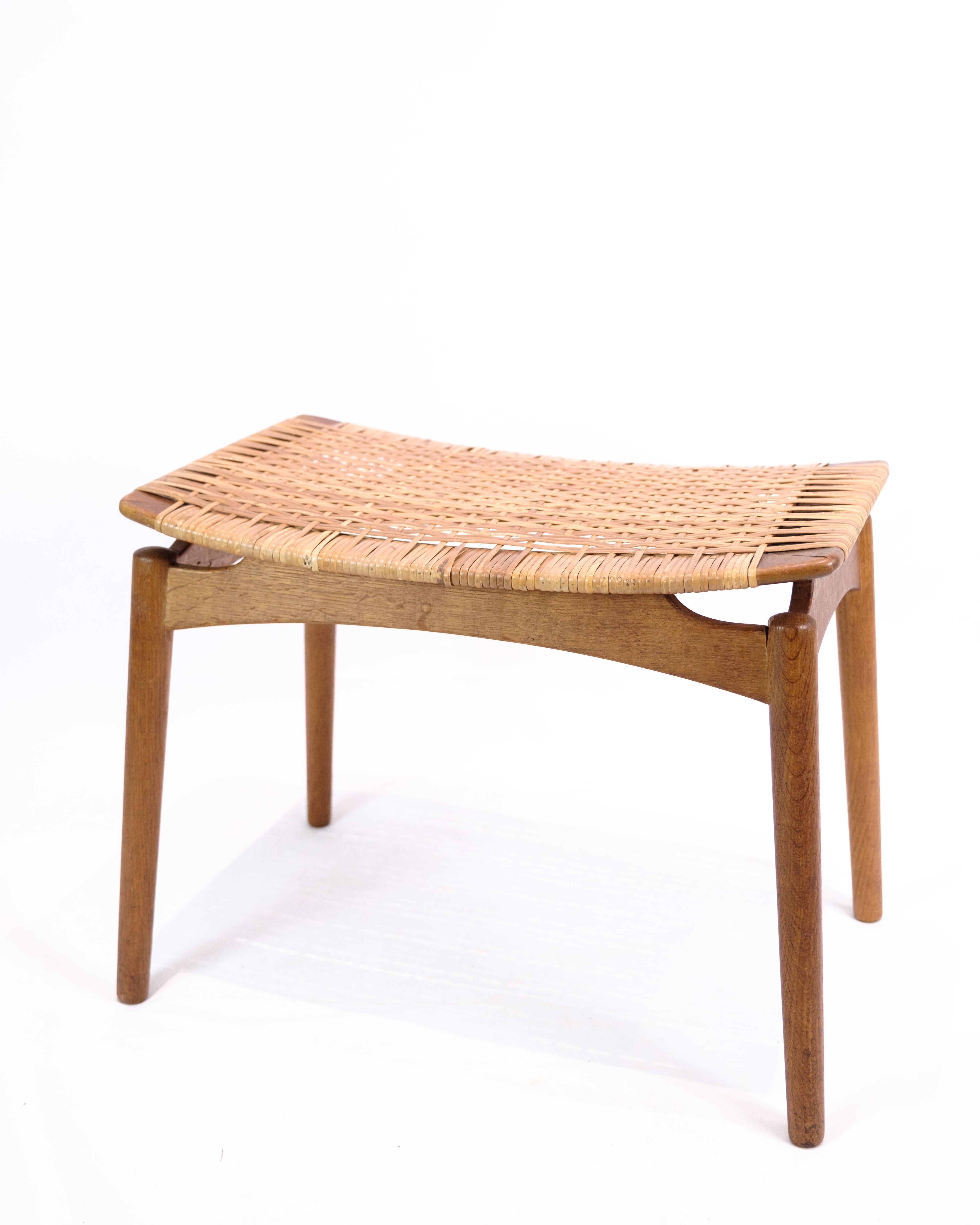 Hocker aus Eichenholz mit Caning, entworfen von Sigfred Omann für die Ølholm Møbelfabrik in den 1960er Jahren. Der Hocker kombiniert Massivholz mit einer handgeflochtenen Sitzfläche, was ihm sowohl Stärke als auch Eleganz verleiht. Sigfred Omann ist