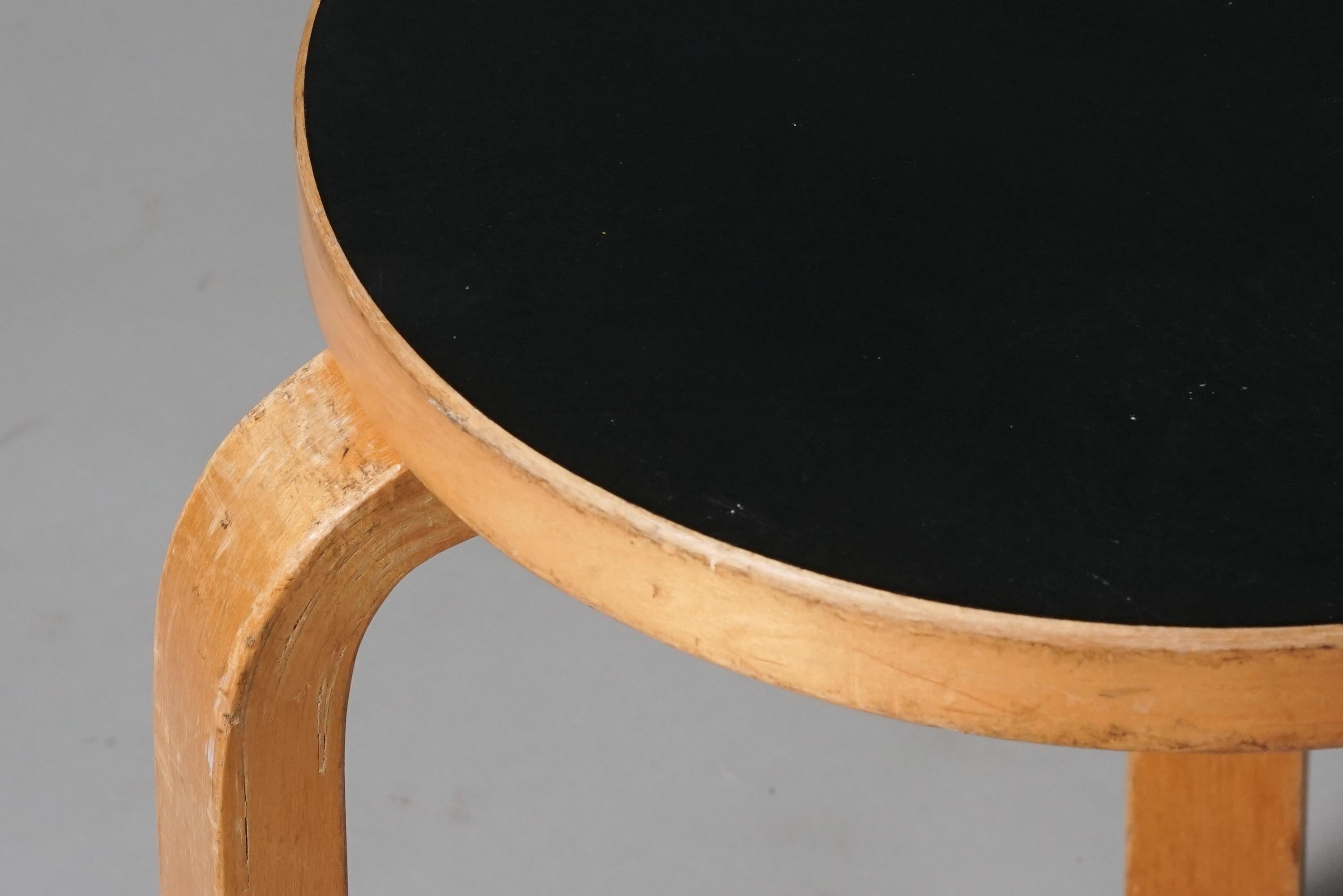 Hocker Modell 60, entworfen von Alvar Aalto, hergestellt von Oy Huonekalu- ja Rakennustyötehdas Ab, 1950er Jahre. Gestell aus Birke mit Sitz aus schwarzem Linoleum. Guter Vintage-Zustand, Patina und Abnutzung im Einklang mit Alter und Gebrauch.