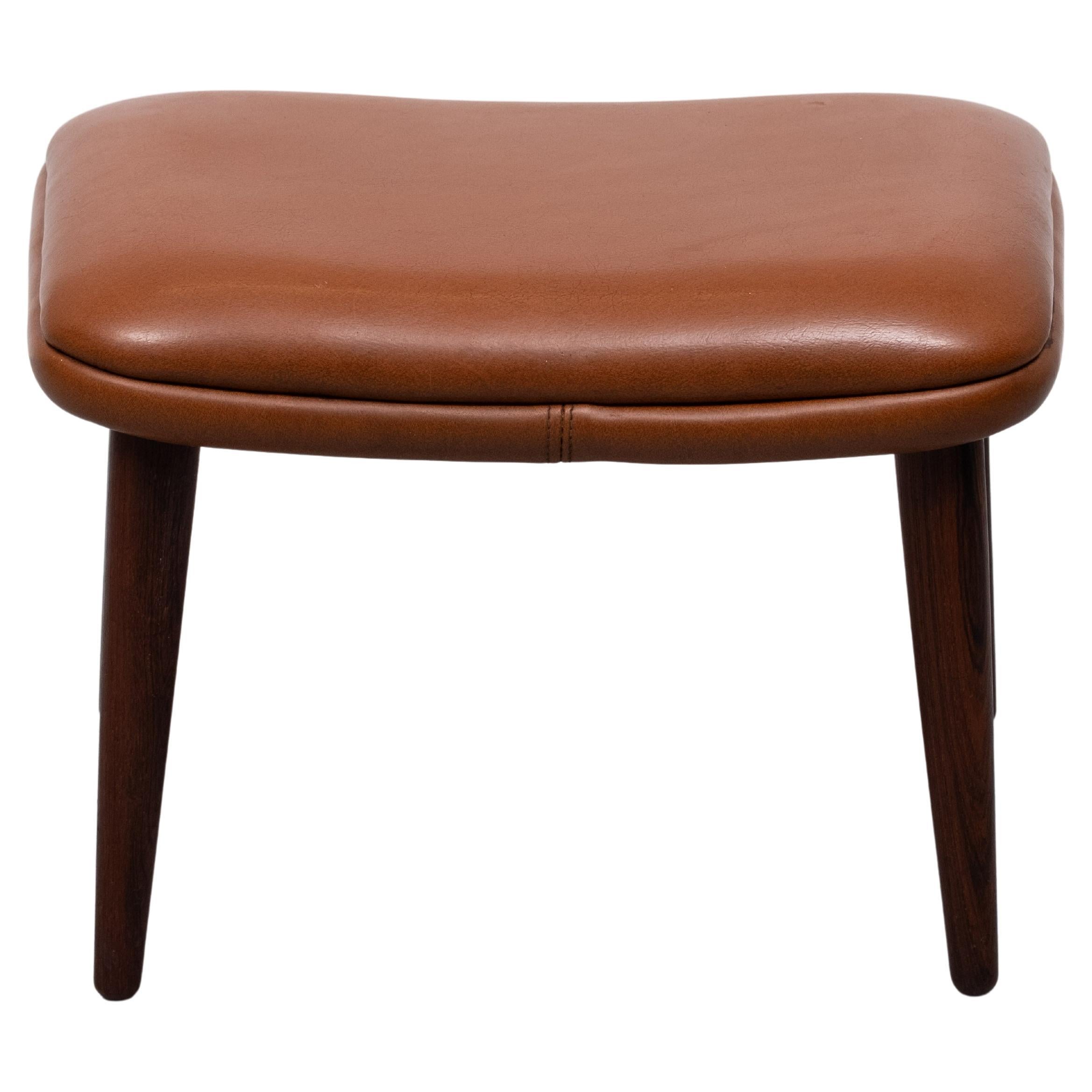 Very nice original Illum Wikkelso foot stool model 91  for Michael Michael Laursen in Aarhus . Solid Rosewood legs , ,comes with its original faux Leather cognac color upholstery .
