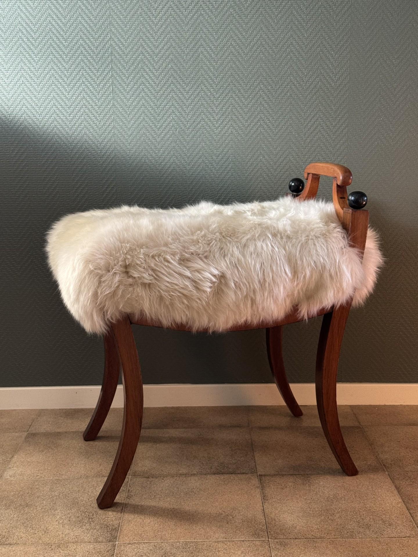 Maravilloso taburete de estilo Imperio o Karl Johan sueco, retapizado con piel de oveja. La altura del asiento es de unos 48 cm, y las dimensiones totales son 57 x 43 cm. El taburete está en muy buen estado y se ha retapizado recientemente. Hay