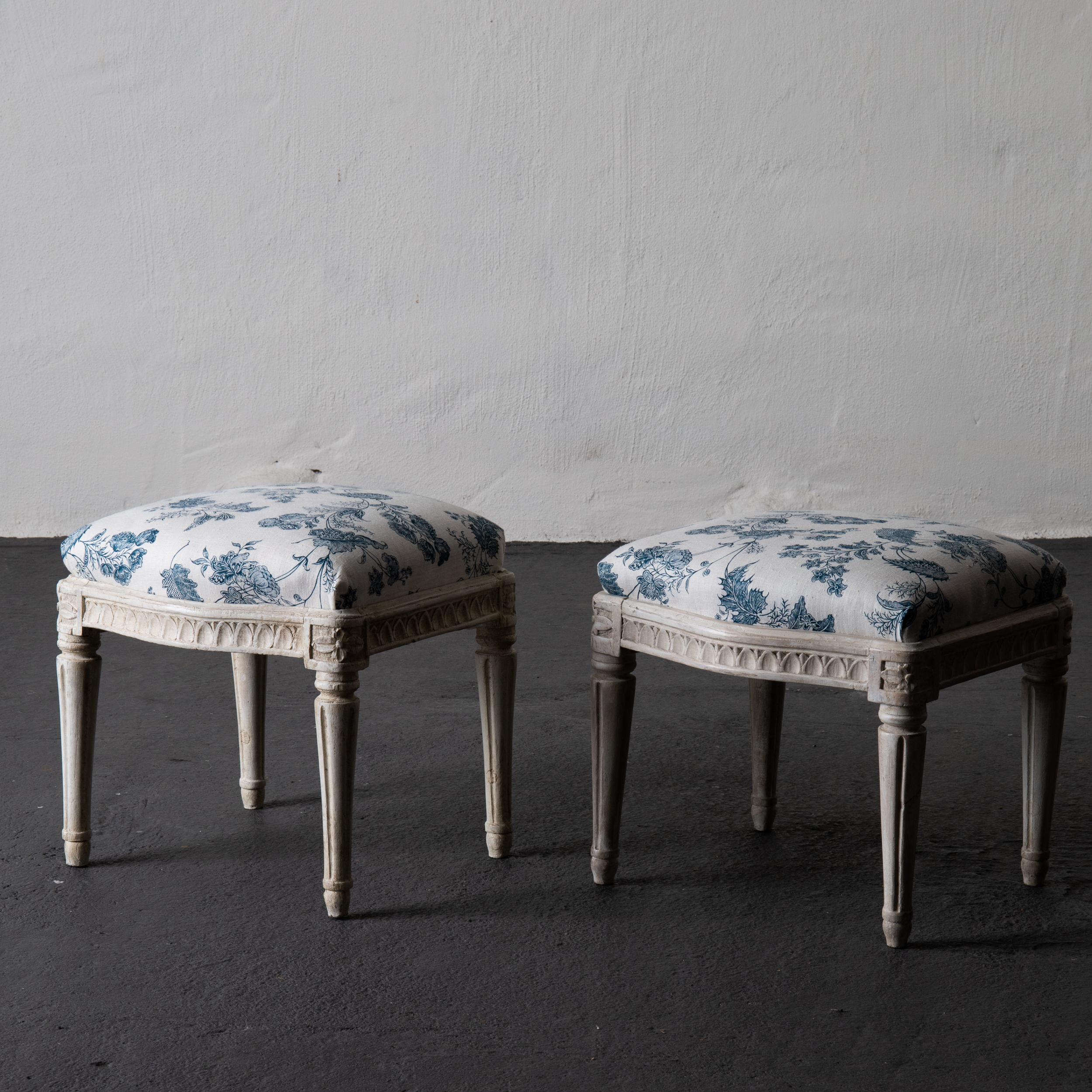 A pair of stools made during the early Gustavian period in Sweden, circa 1780-1790. Semi curved frieze decorated with carved leaf tips. Rounded and channeled legs. One of the stools have the Royal HGK mark. Upholstered in a blue and white floral