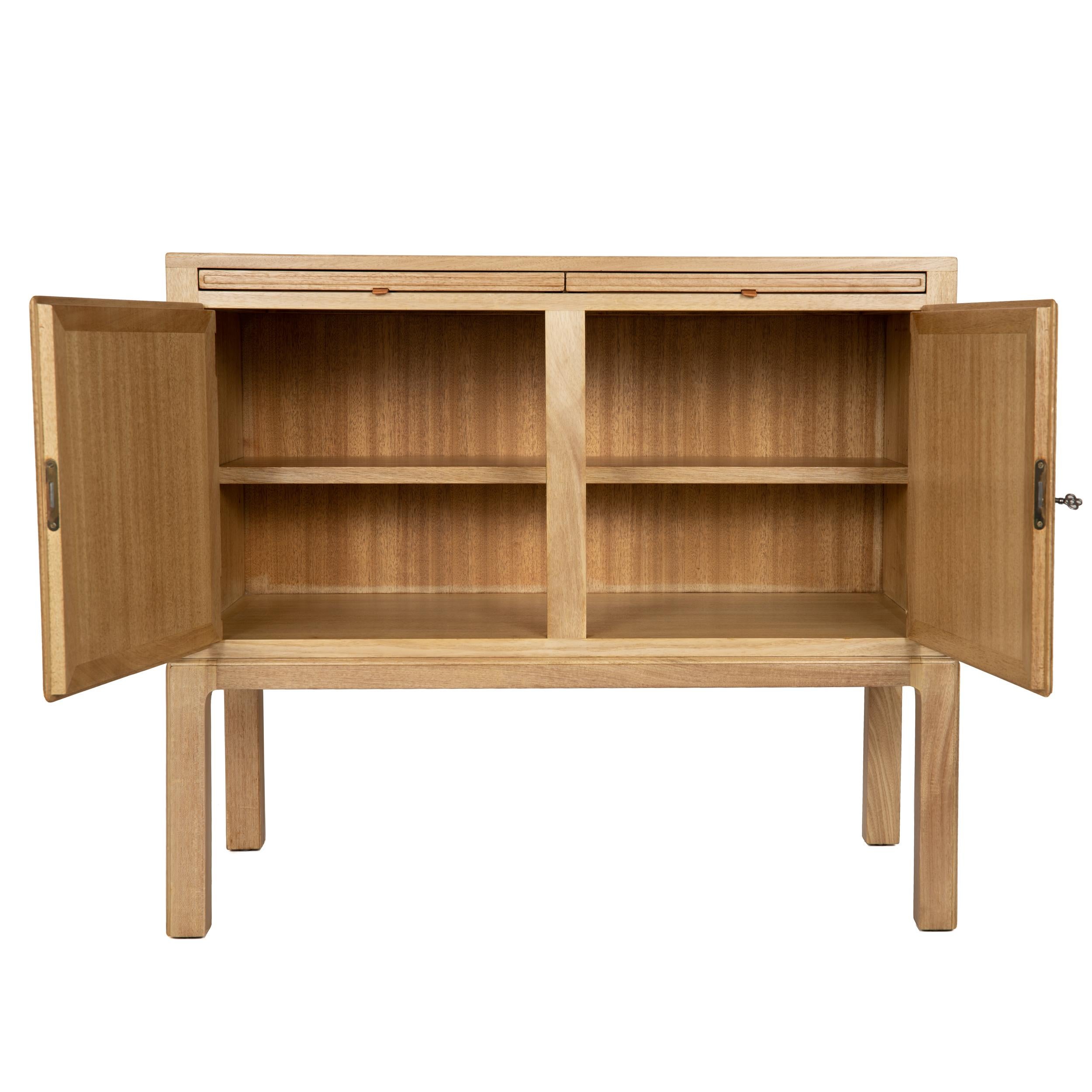 A simple cabinet with two leather tabbed pull-out shelves over two locking doors which revel an adjustable interior shelf.