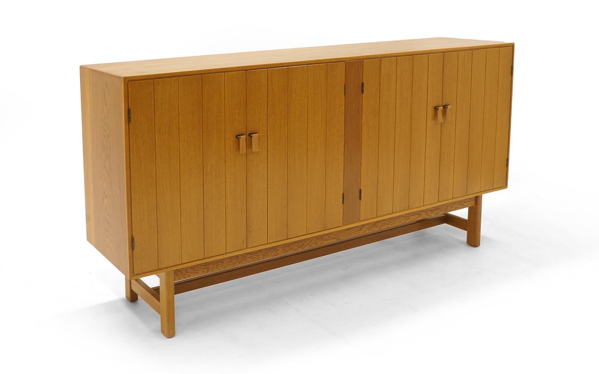 Large scale cabinet or sideboard by Kurt Ostervig for H. C. Mobler, Denmark, 1960. Cabinet features four doors concealing five removable trays and six adjustable shelves. Signed with applied manufacturer’s mark to reverse of cabinet: [H.C. Møbler,