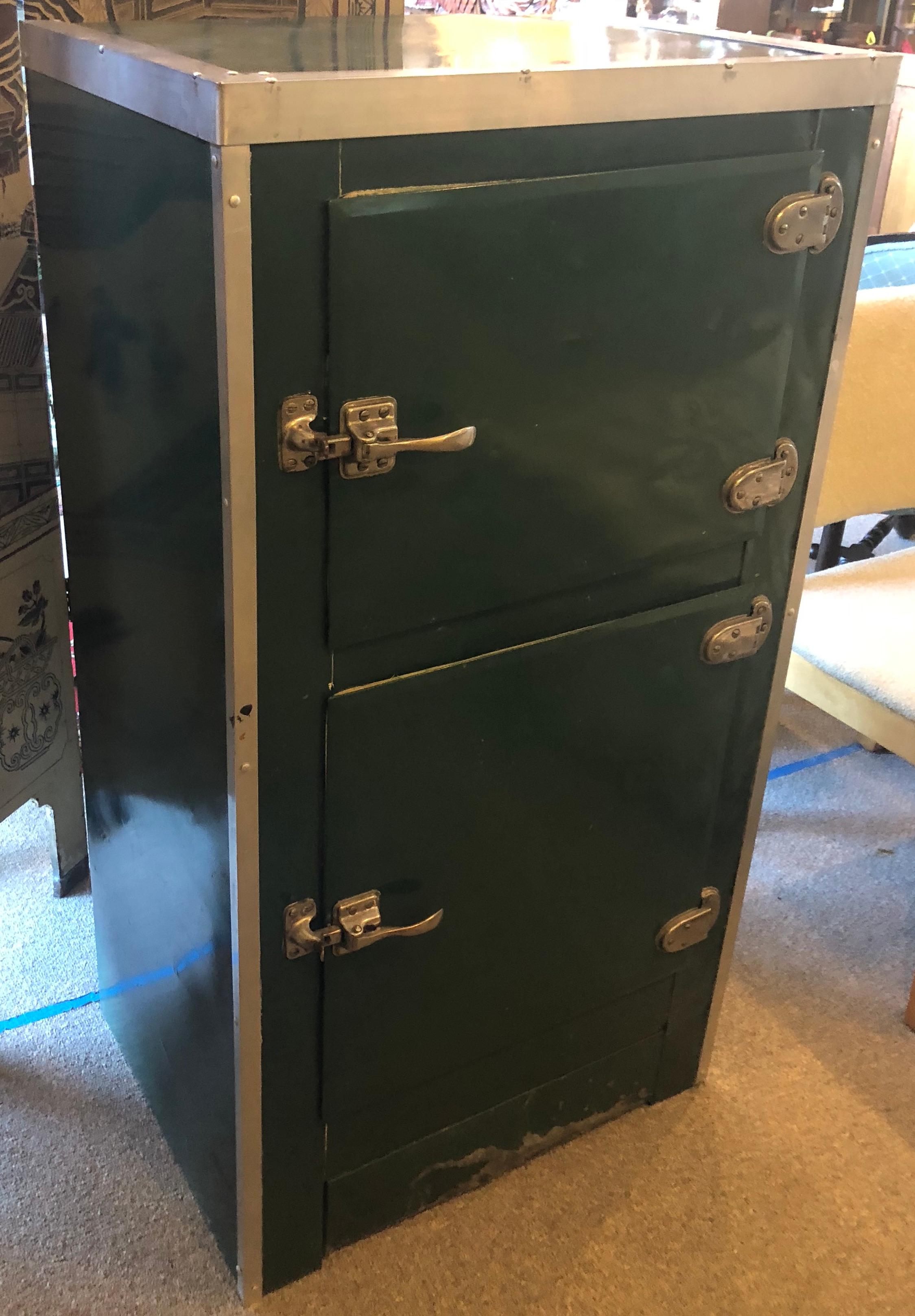 Storage cabinet from porcelain ice box in good condition with some character marks of time and use, circa 1930s. Lovely spruce green wrapped porcelain around wooden frame with aluminum trim and steel handles on doors. Ideal home bar. How about a