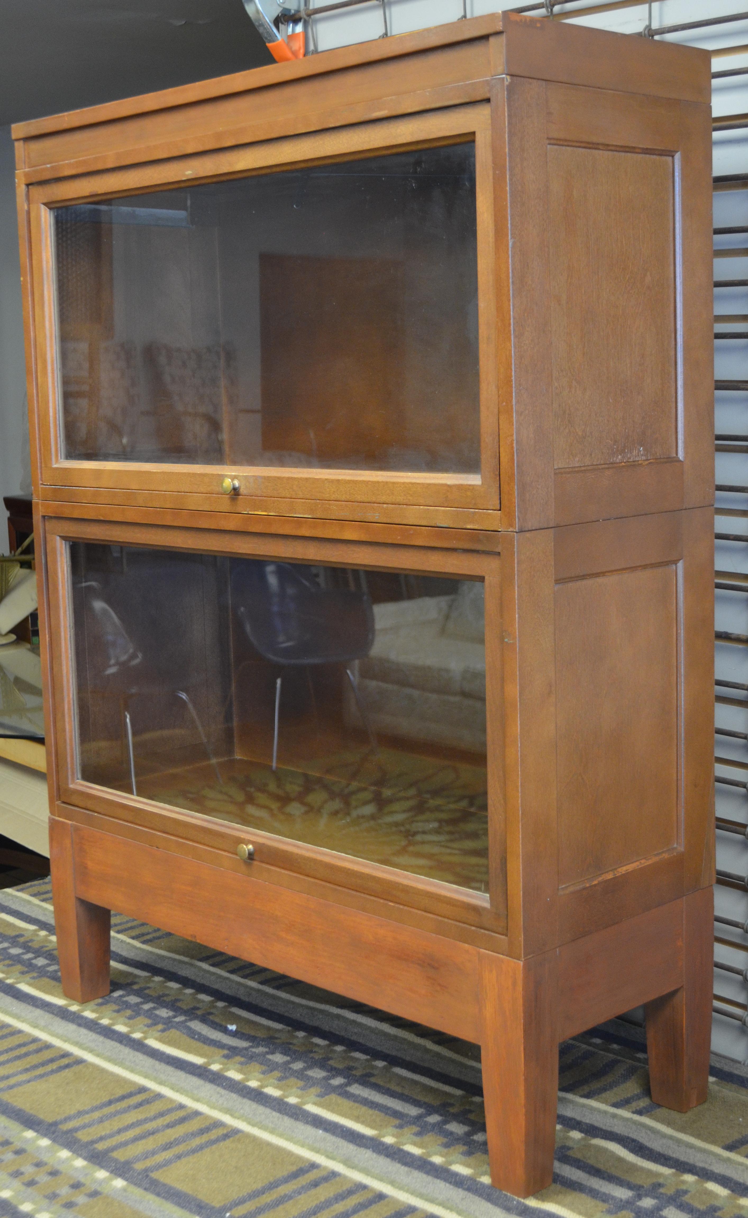 Storage cabinet, lawyer's barrister of wood and glass. Two stacking units with base and top. Glass fronts with brass knobs are retractable on sliders, lift up and gently push in. Work smoothly. Excellent vintage condition with character patina of