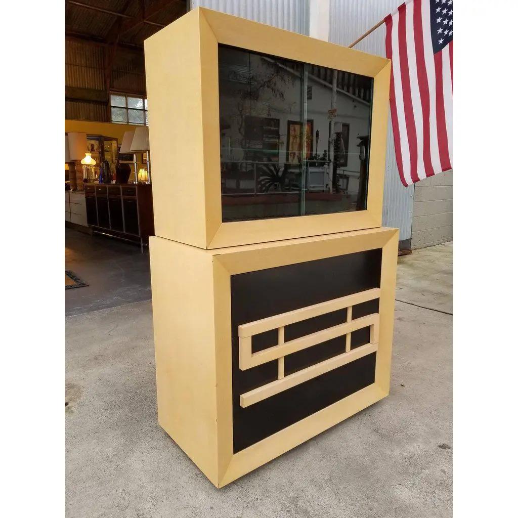 Karp Furniture Los Angeles, California. A Paul Frankl style storage or China cabinet with a contrasting blonde and lacquered black finish. Pulls form geometric, maze-like pattern. Two stacking cabinets consisting of a three-drawer base and a sliding