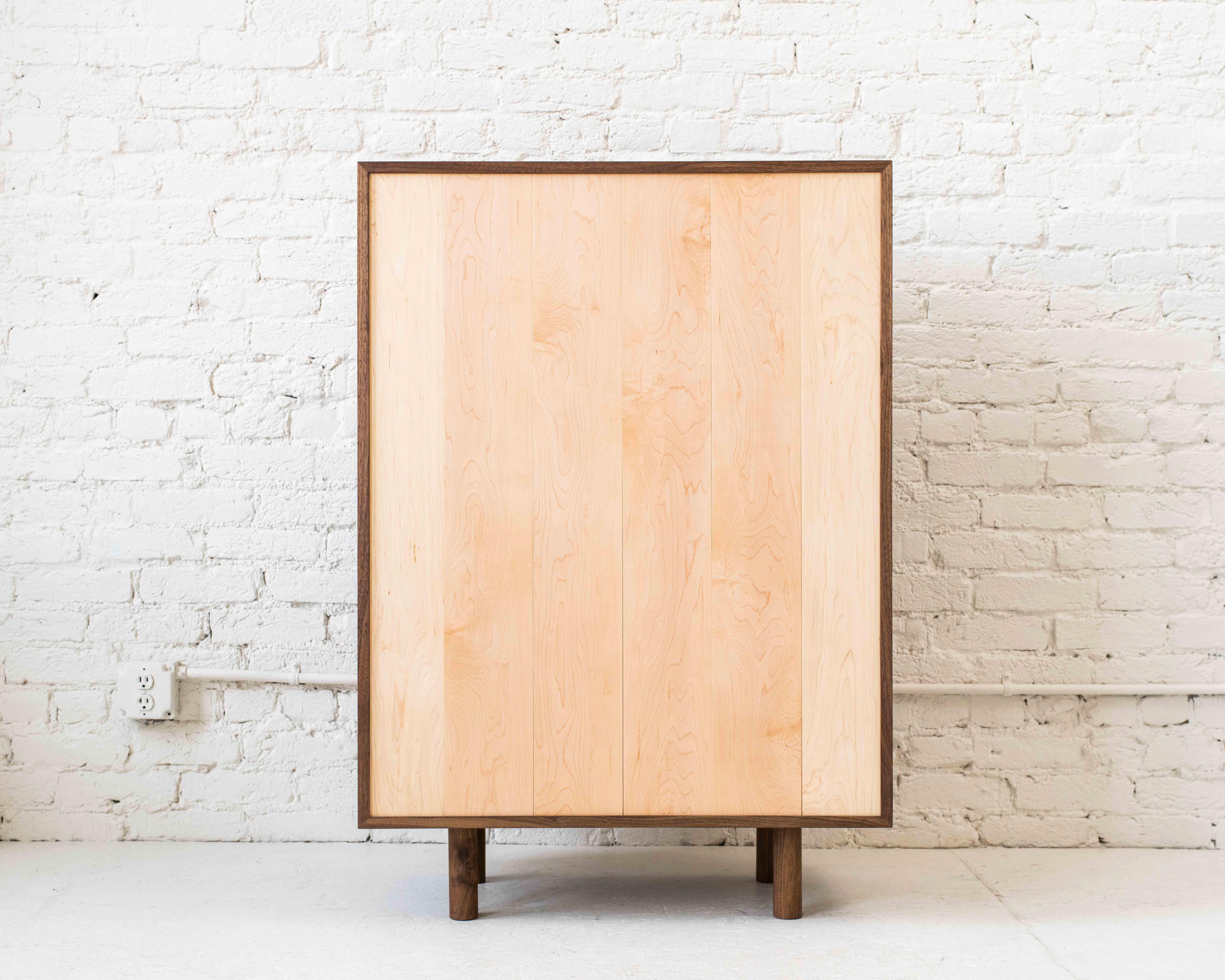 Storage cupboard one by Campagna. Shown in walnut and maple. 

Drawing influence from Shaker cabinetry and Japanese woodworking, this solid wood storage cabinet is minimal in form, showcasing the beauty of the natural wood. With a solid maple back