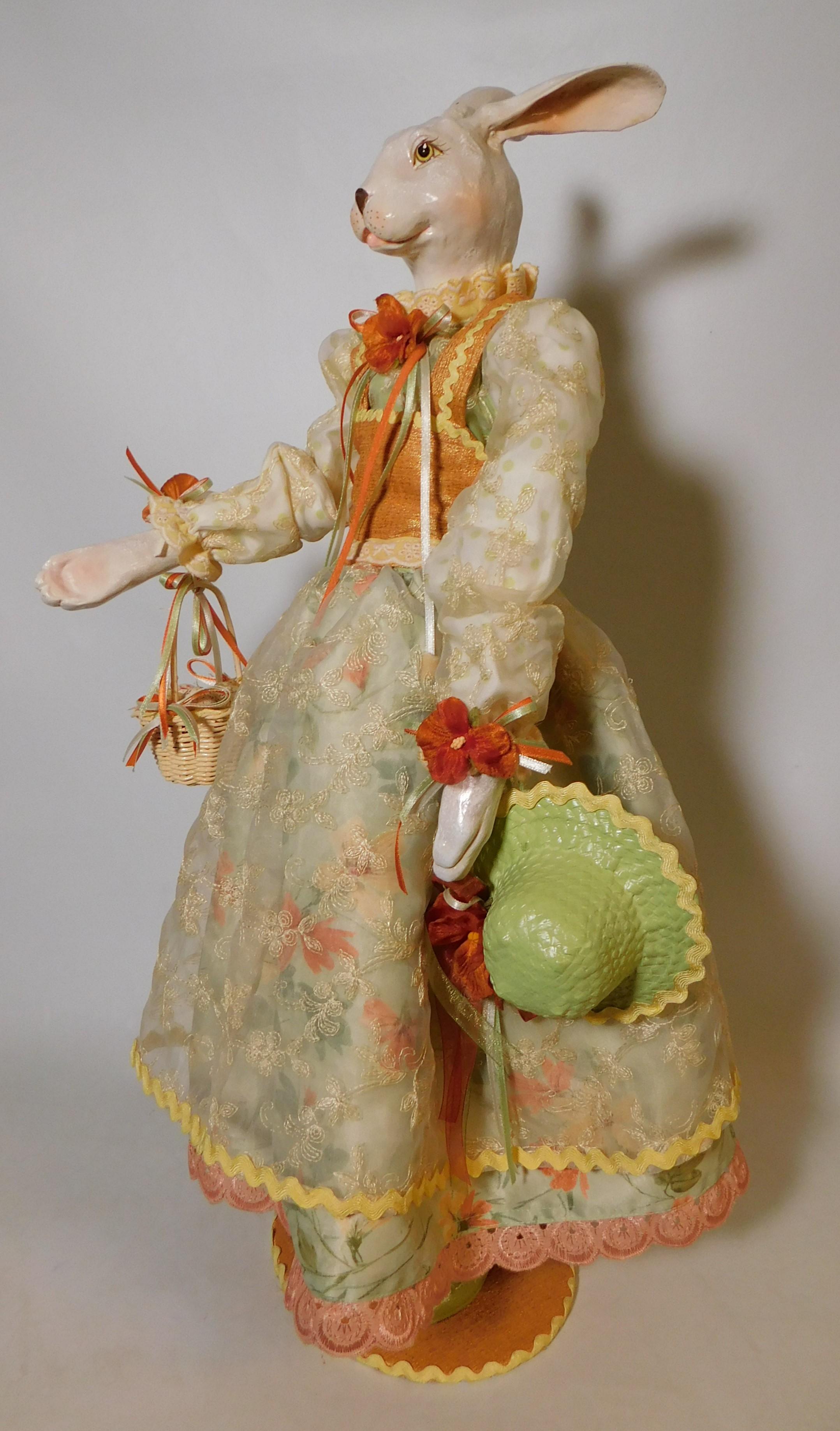 Store display rabbit over two feet high holding a basket with eggs in one hand and an Easter bonnet in the other. The hare appears to be made of a papier-mâché/fiberglass composition.