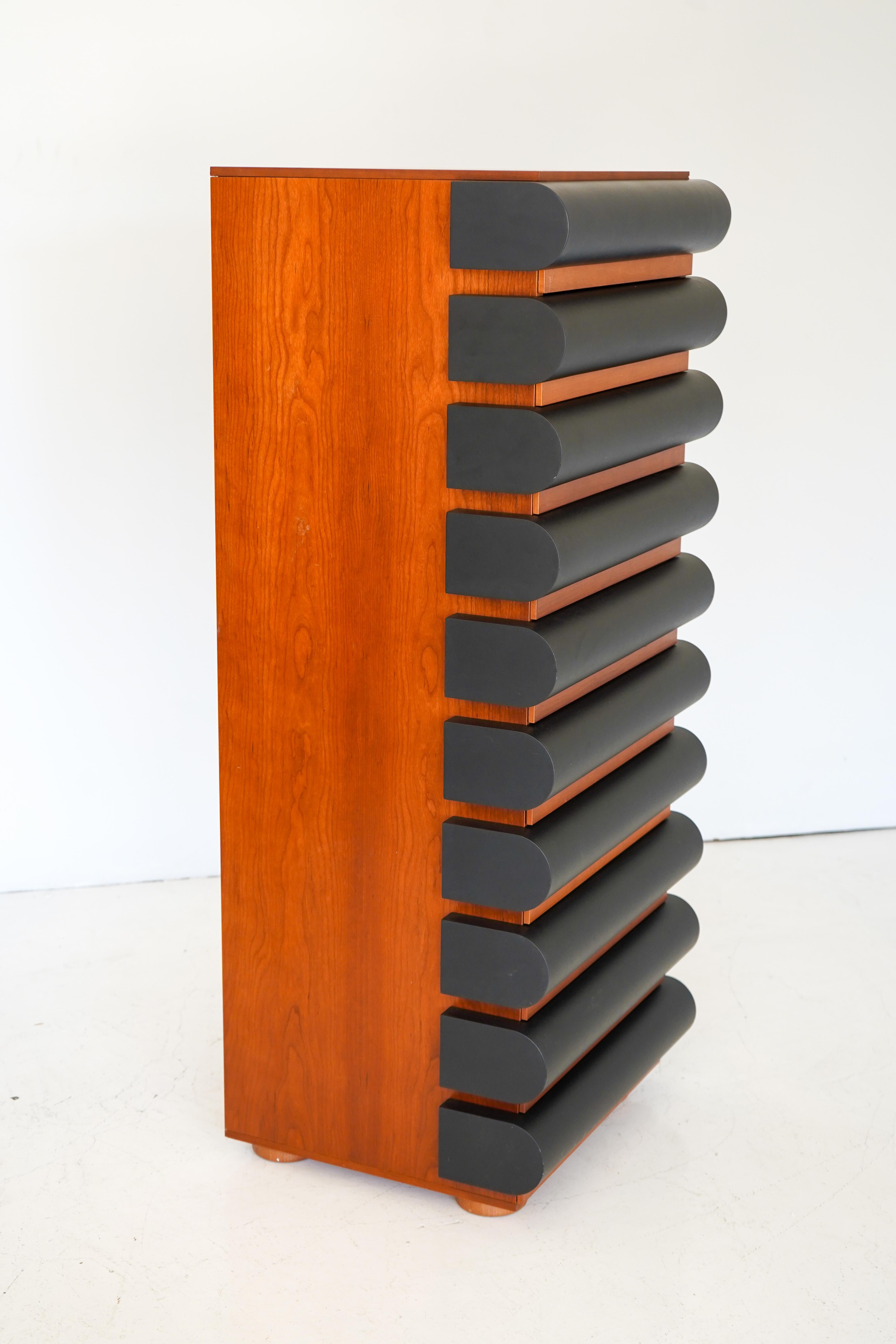 Cassettiera High Storet in noce e nero di Nanda Vigo per Acerbis, 1994.

Conosciuta per il suo lavoro nelle arti visive, nel design e nell'architettura, Nanda Vigo è stata una polimatica italiana all'avanguardia, molto avanti rispetto ai suoi tempi.