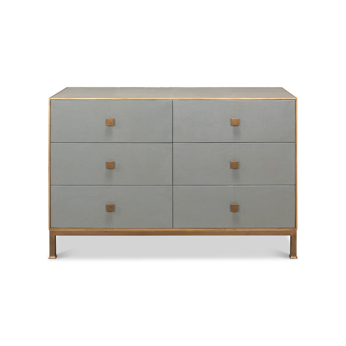 This chic piece showcases an embossed gray leather facade accented by elegant gold trim and hardware. With six spacious drawers that provide ample storage. Its minimalist design is punctuated by square brass handles that add a touch of glamour,