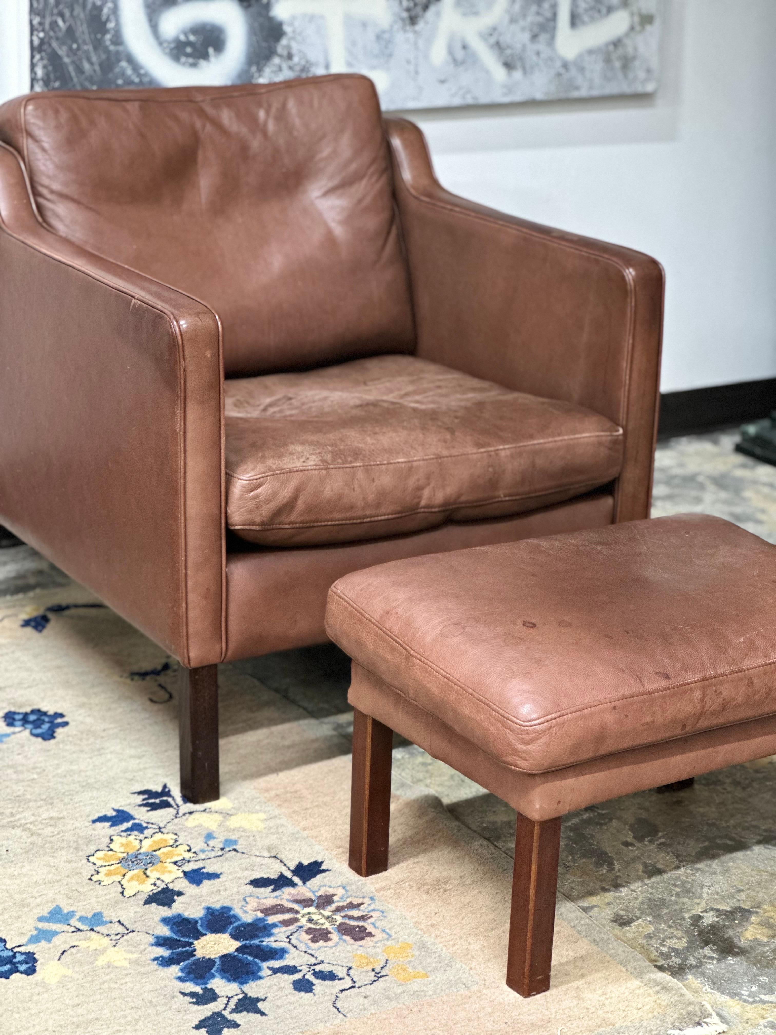 Leather chair and ottoman by Stouby. Minor staining and discoloration consistent with age. One blemish on chair left arm from adhesive of tape.

Ottoman measurments:
16