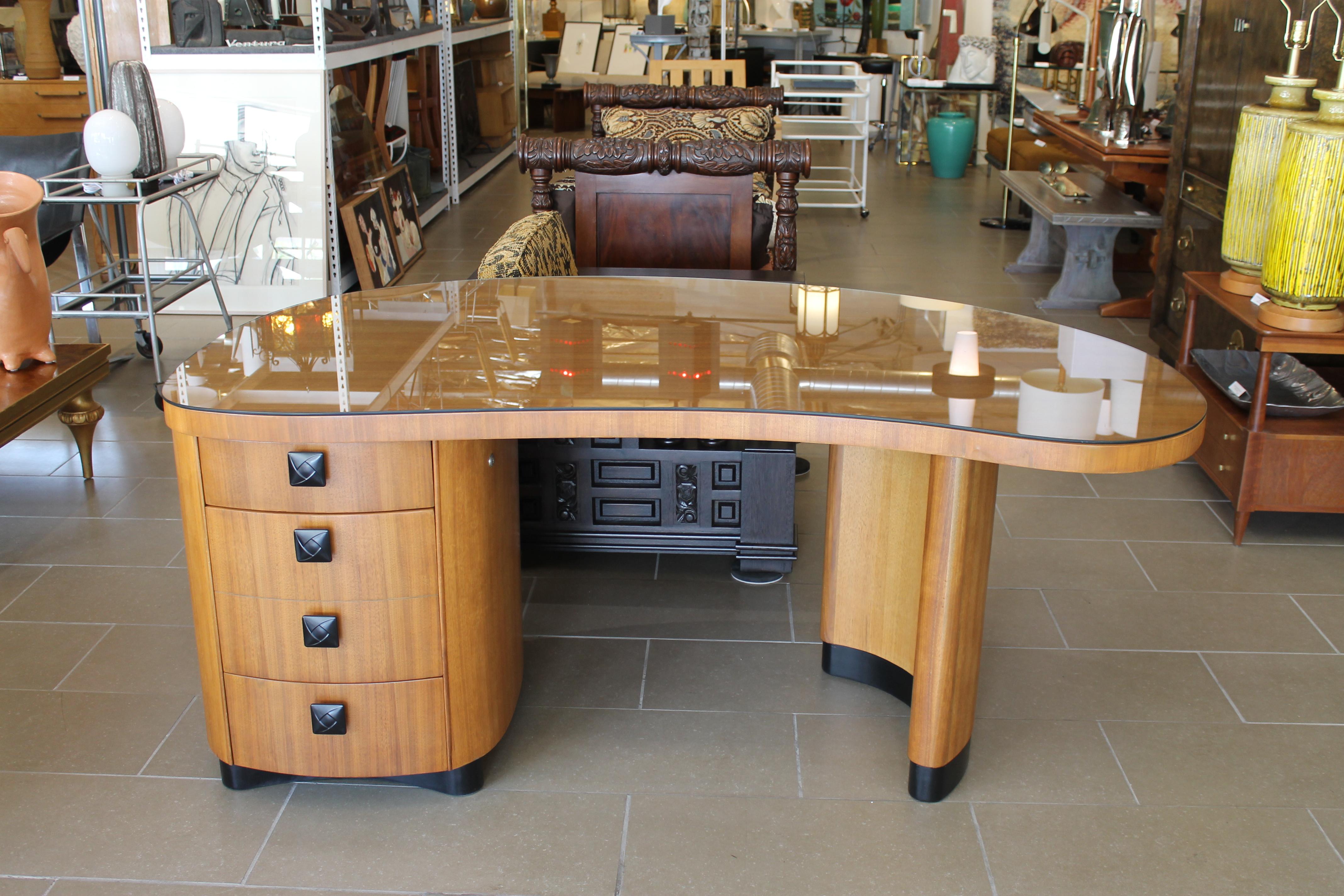 Kidney shaped Stow & Davis desk with glass top. Label on top drawer says Stow & Davis Furniture Company, Grand Rapids, Michigan. We believe this desk is a walnut and mahogany. Desk measures 29