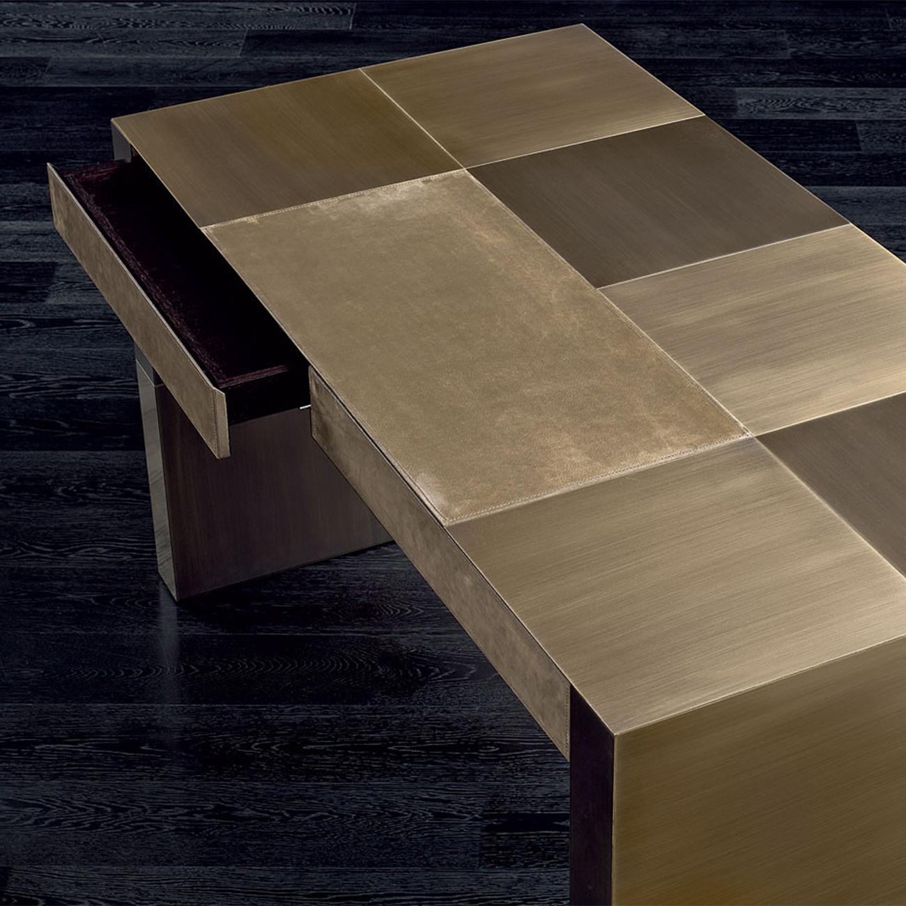 Desk Strada with structure in solid wood covered with
bronze plates in brush finish with 2 different shades of 
brushed bronze finish. Desk pad covered with high quality
genuine suede leather in bronze color finish. Desk including
2 drawers with