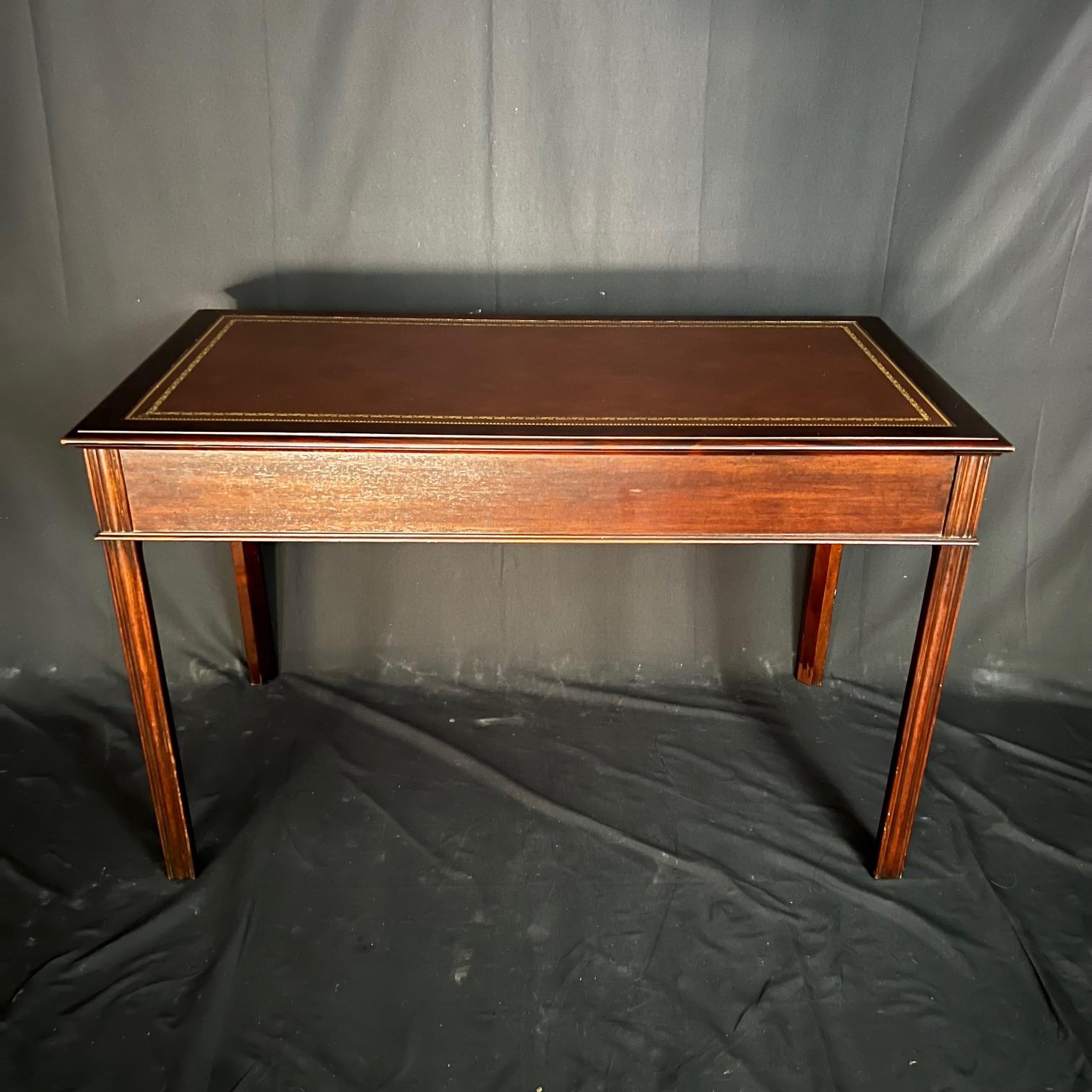 This is a vintage traditional mahogany library desk or writing table. Its design was inspired by Chippendale desks from the Regency period and features classic straight legs. It also features drawers and a top with swirly crotch mahogany fields and