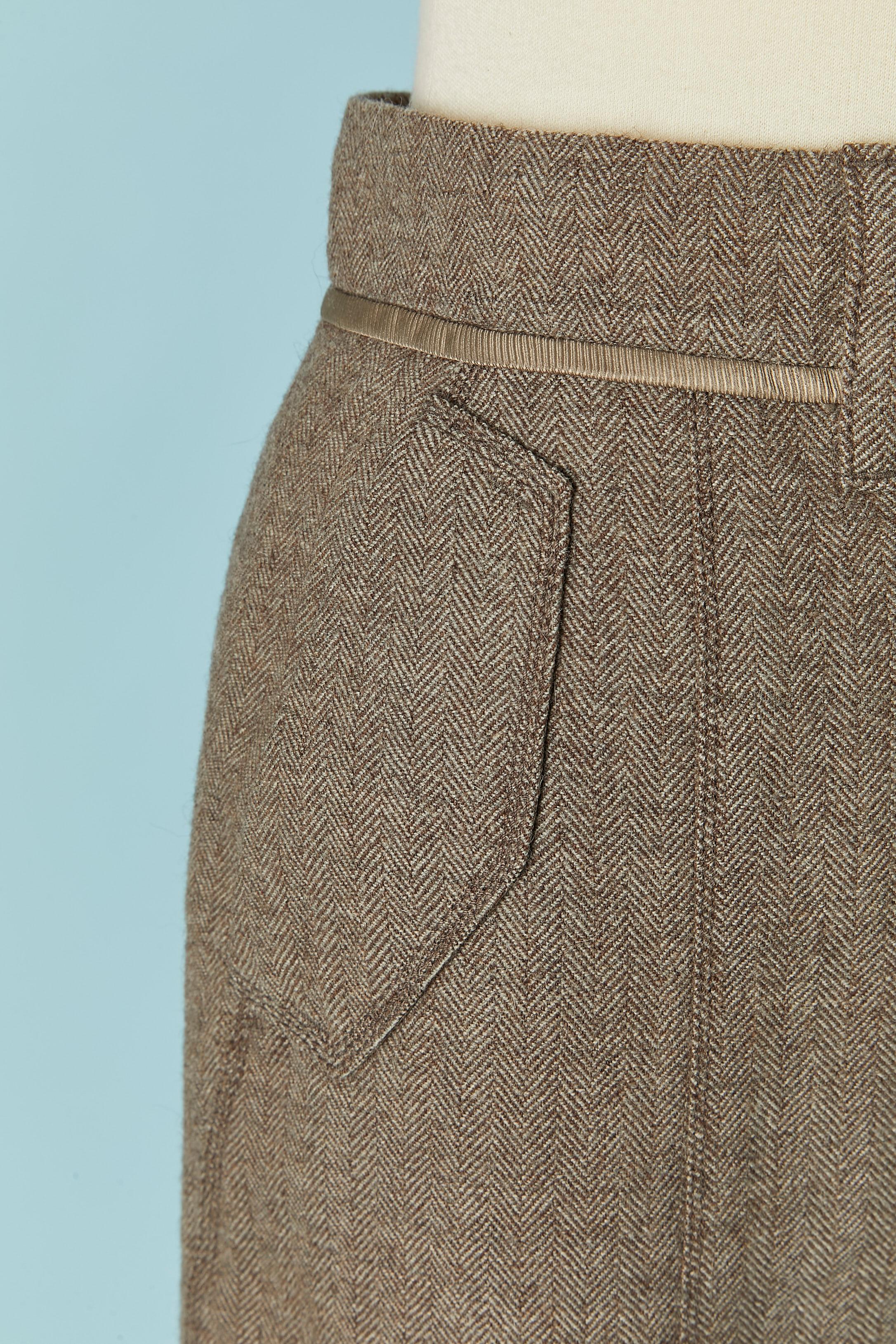 Falda recta de lana beige chevron. Composición del tejido principal: 80% lana, 20% alpaca. Forro de seda 
Cierre con corchetes y cremallera en la parte superior central delantera. 2 bolsillos laterales y 2 bolsillos traseros con cierre de