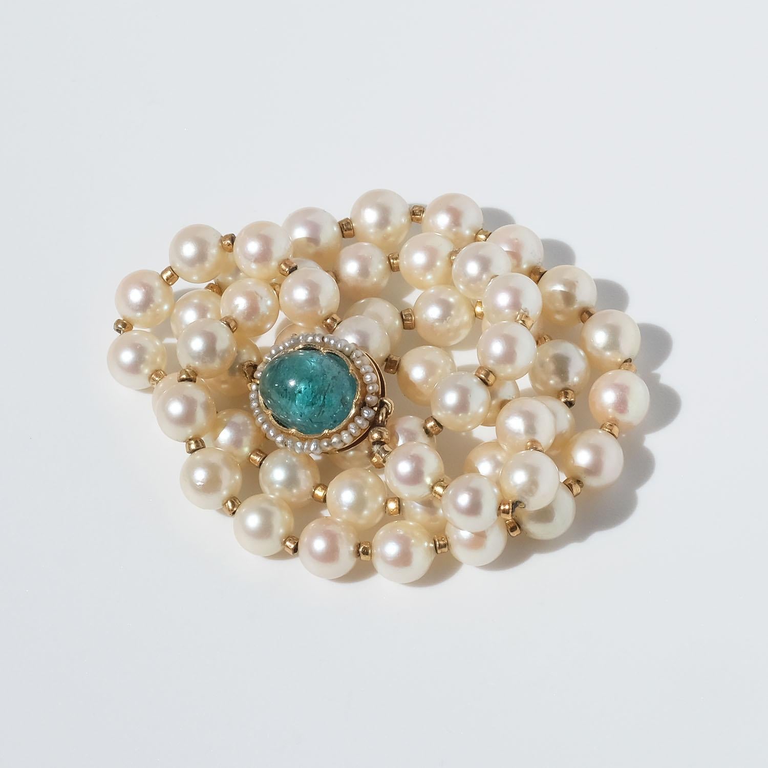 Diese Perlenkette besteht aus Zuchtperlen mit einer schönen Perlmuttfarbe. Zwischen jeder Perle befinden sich kleine vergoldete Glieder. Das Collier wird mit einem Verschluss aus 18 Karat Gold geschlossen, der mit einem Aquamarin im Cabochon-Schliff