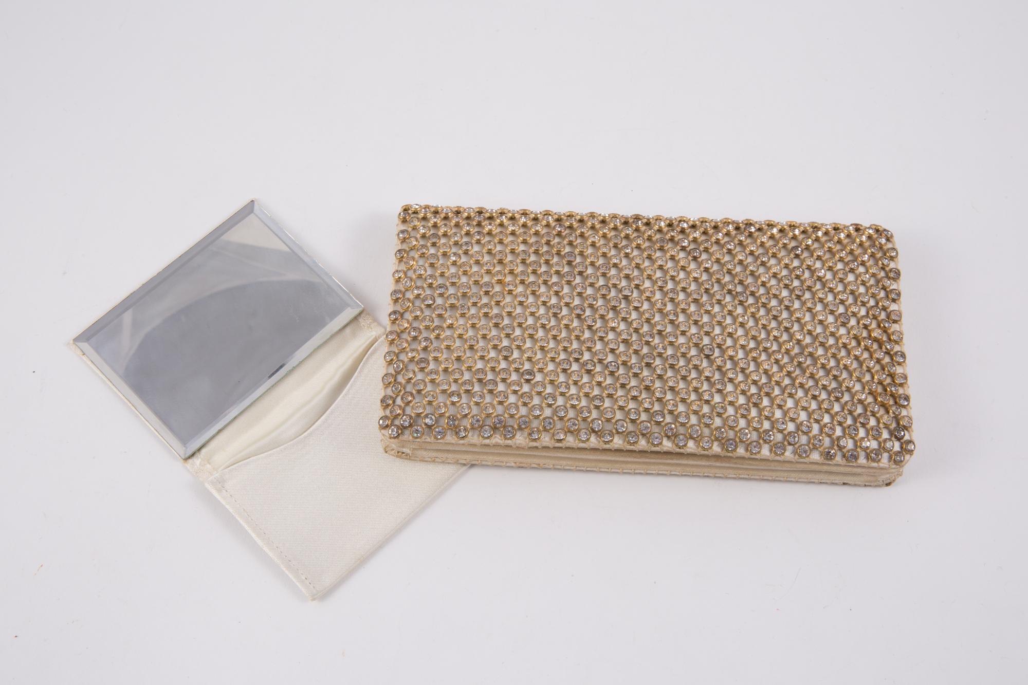 1960 evening ivory silk clutch bag featuring a full strass pattern with gold tone outlines, inside compartments, a snap closure and a separated mirror.
Length 6.7in. (17cm)
Height 3.5in. (9cm)
Depth 1.18in. (3cm) 
In good vintage condition. Made in