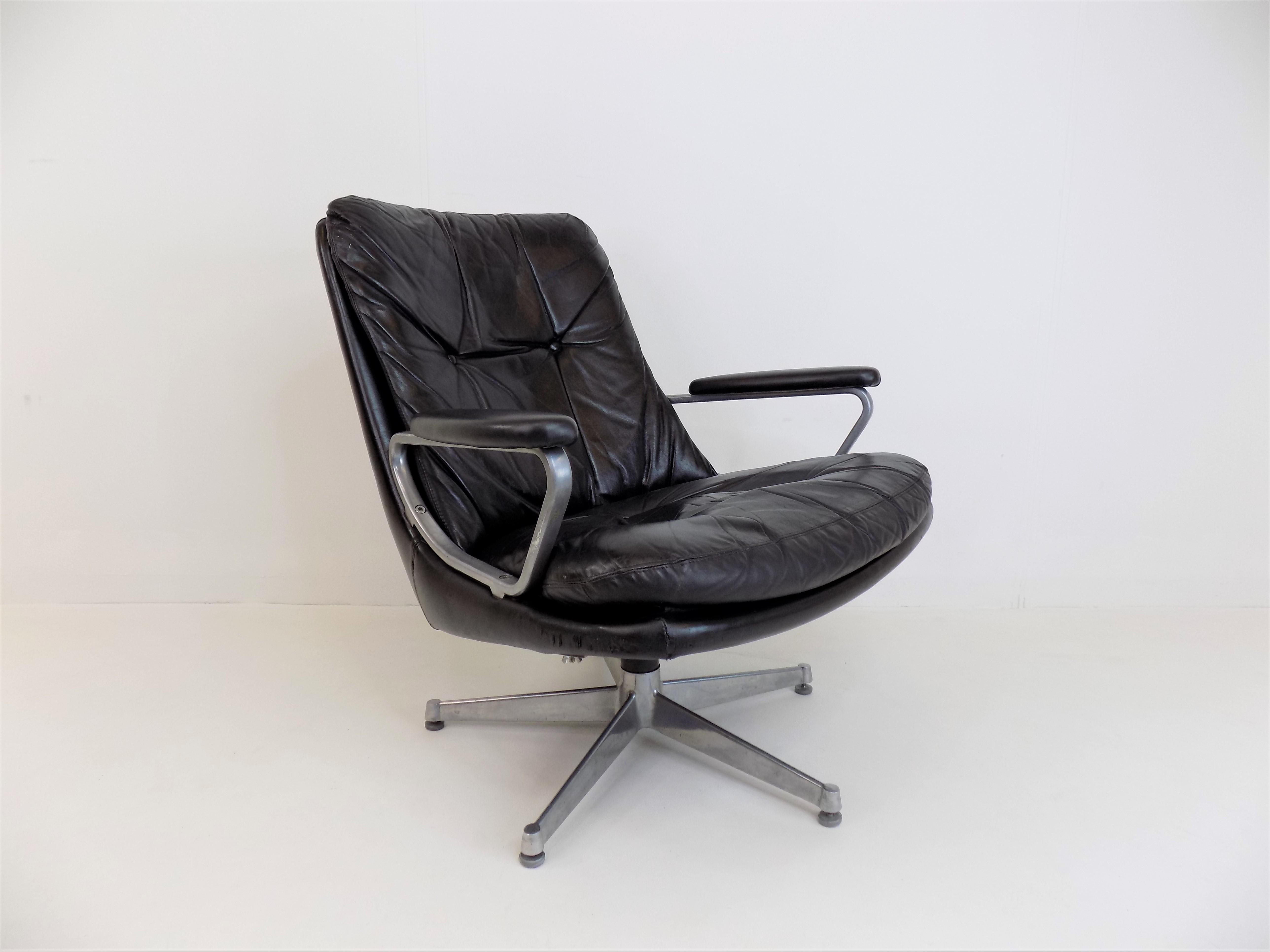 This Gentilina leather armchair in black leather is in good condition. The leather and the stainless steel backrests show minimal signs of wear. The backrest has a slight scratch, the front corners have abrasions. Andre Vandenbeuck designed this