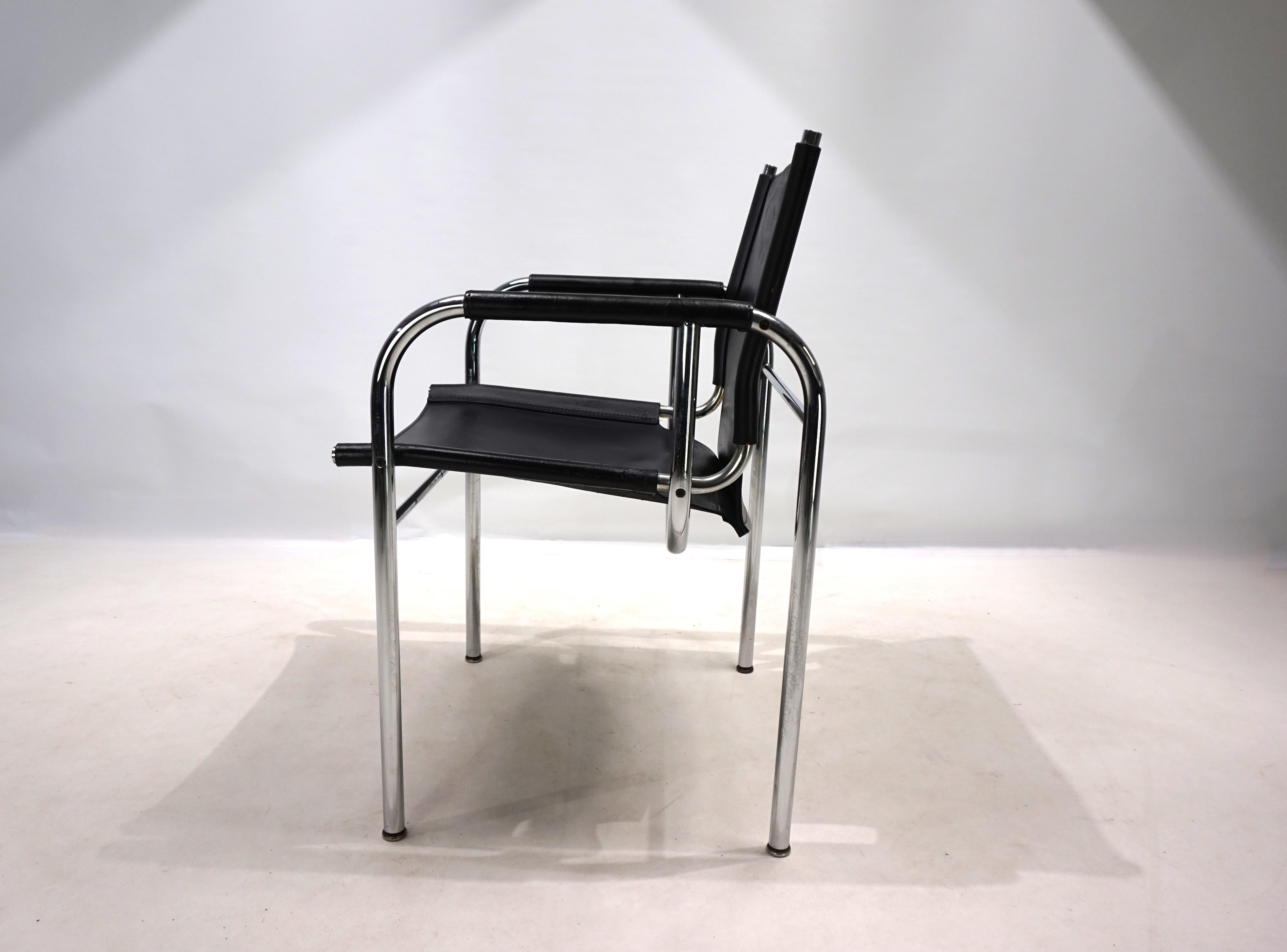Sillón de cuero Strässle HE de los años 60, en buen estado pero con una pátina evidente. La piel del sillón, de un tono negro intenso, está rugosa en algunas partes y tiene craqueladuras en la piel del respaldo. El marco cromado está en muy buen