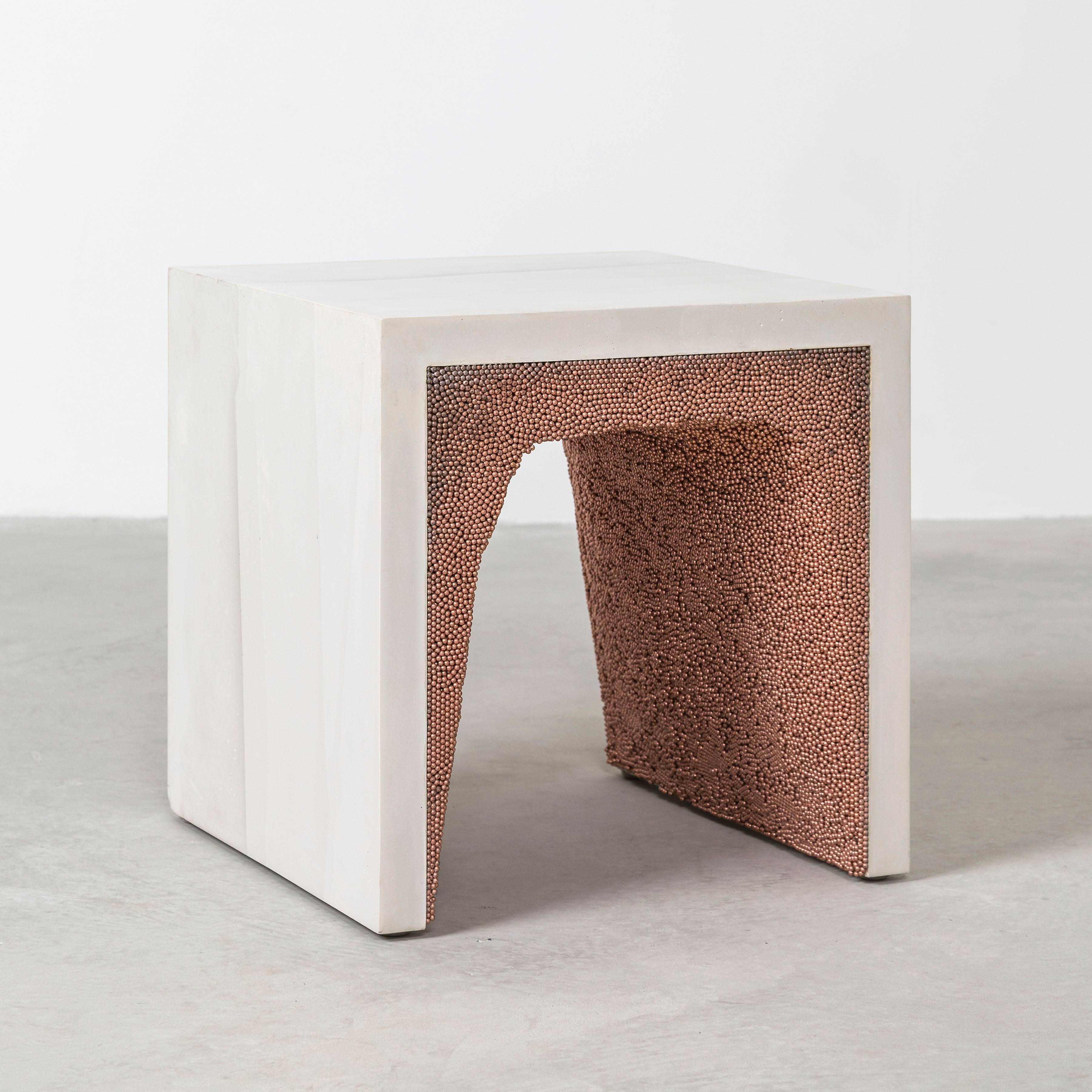 Composed from a combination of materials, the angular side table consists of a hand-dyed cement exterior and a copper BB interior. Packed by hand within the smooth ombre of cement, the granules form an organic texture to contrast the structural
