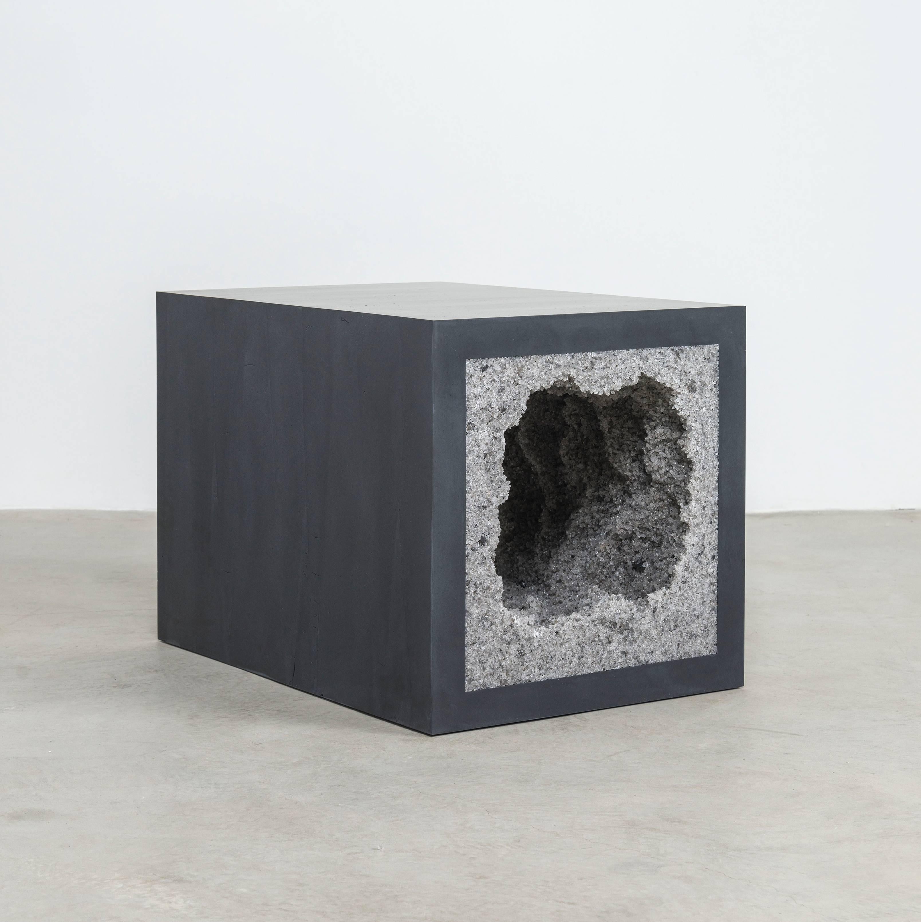 Composed from a combination of materials, the angular side table consists of a hand-dyed cement exterior and a grey rock salt interior. Packed by hand within the smooth ombre of black cement, the granules form an organic texture to contrast the