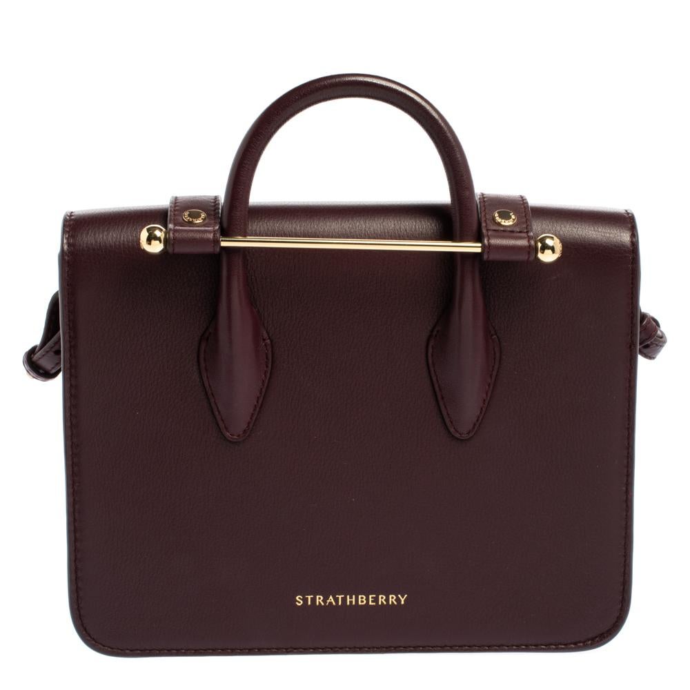 This Strathberry creation is absolutely stunning. It has been designed to deliver sophistication and functionality. Crafted meticulously from quality leather, it flaunts a lovely plum hue. This bag features a single top handle, gold-tone hardware