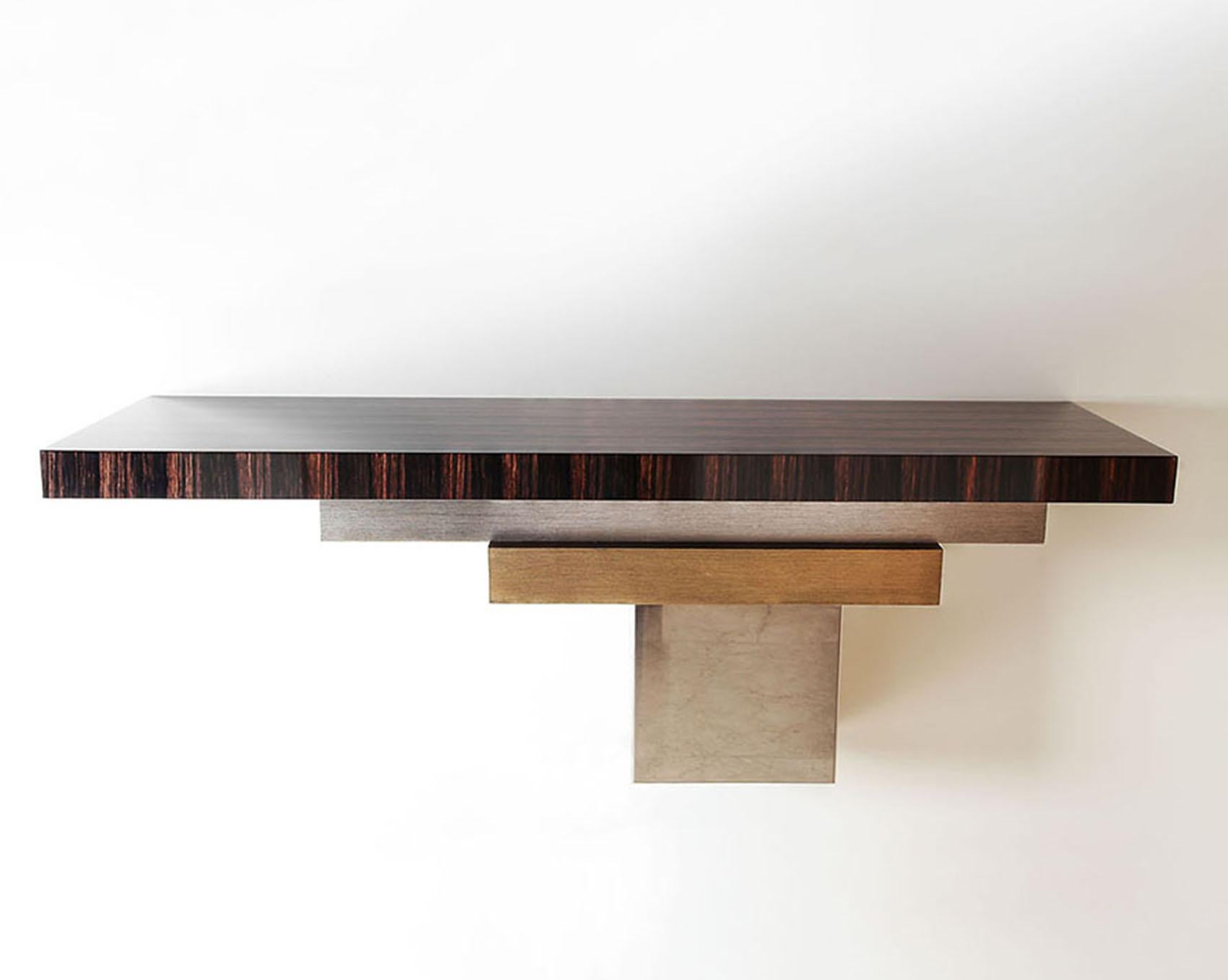 Stratos L, Console - Wall mounted from the Stratos Line
The asymmetrical composition for this console is a wild yet harmonious combination of several metals, wood and lacquer.

Materials: 
Tinted Gray Sycamore 100 % glossy
Hand patinated silver