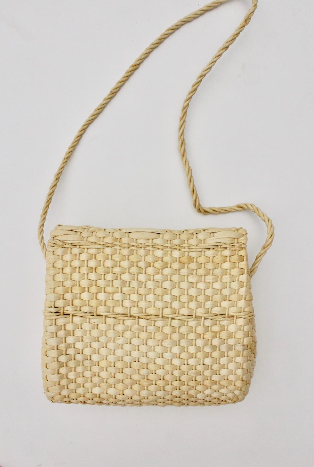 We present a vintage straw shoulder bag with a structured surface made of straw. 
The flap is easy to close with a rattan bow. Furthermore the structured surface shows a woven rhomb pattern.  The shoulder cord measures approx. 50 cm and so it is