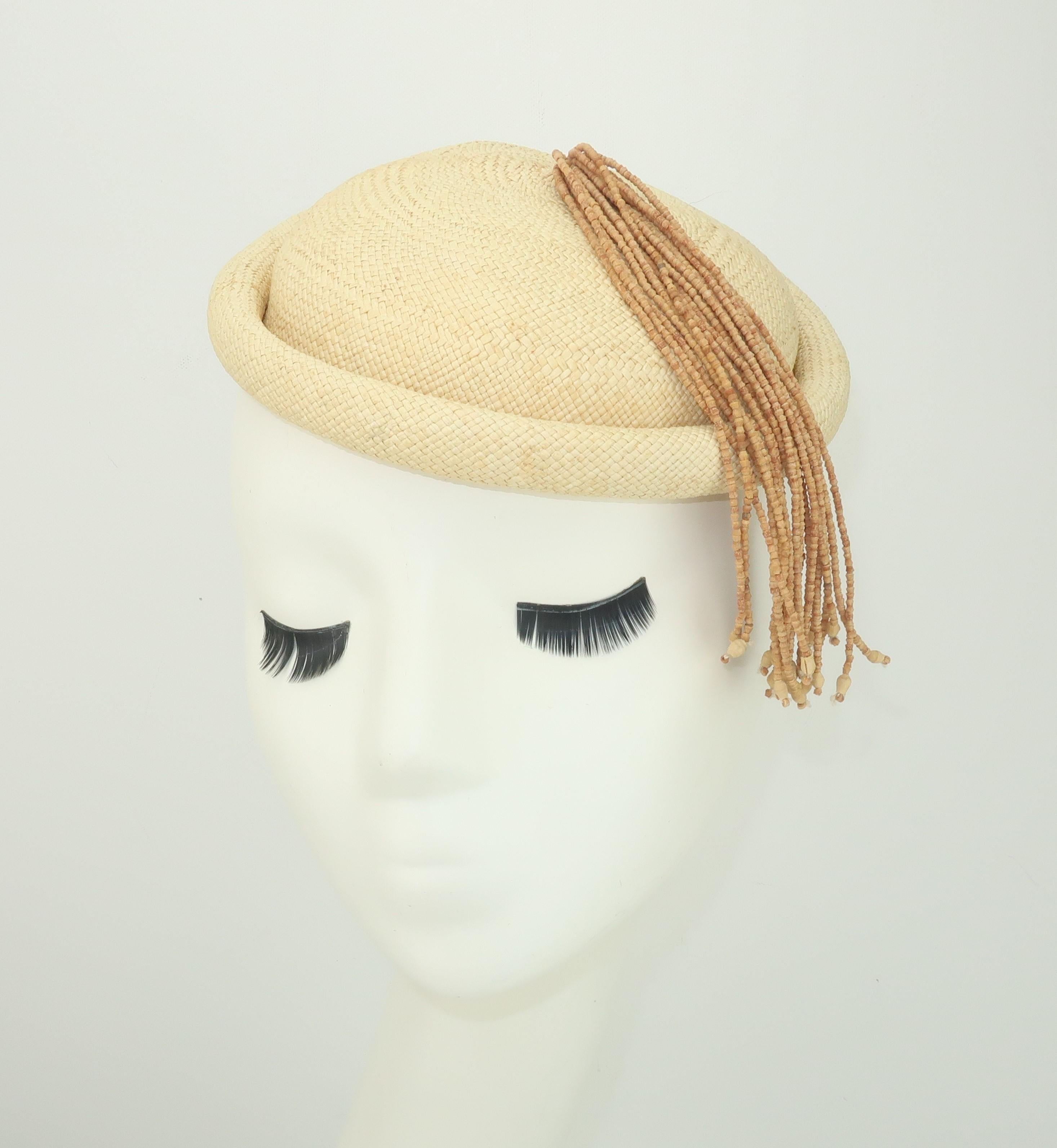 A light natural straw disk shaped fascinator style hat with a wooden beaded tassel finial by Rosemary Peck.  Cute little topper for accessorizing your favorite tropical prints.  From the living estate of an amazing fashionista who was born in the