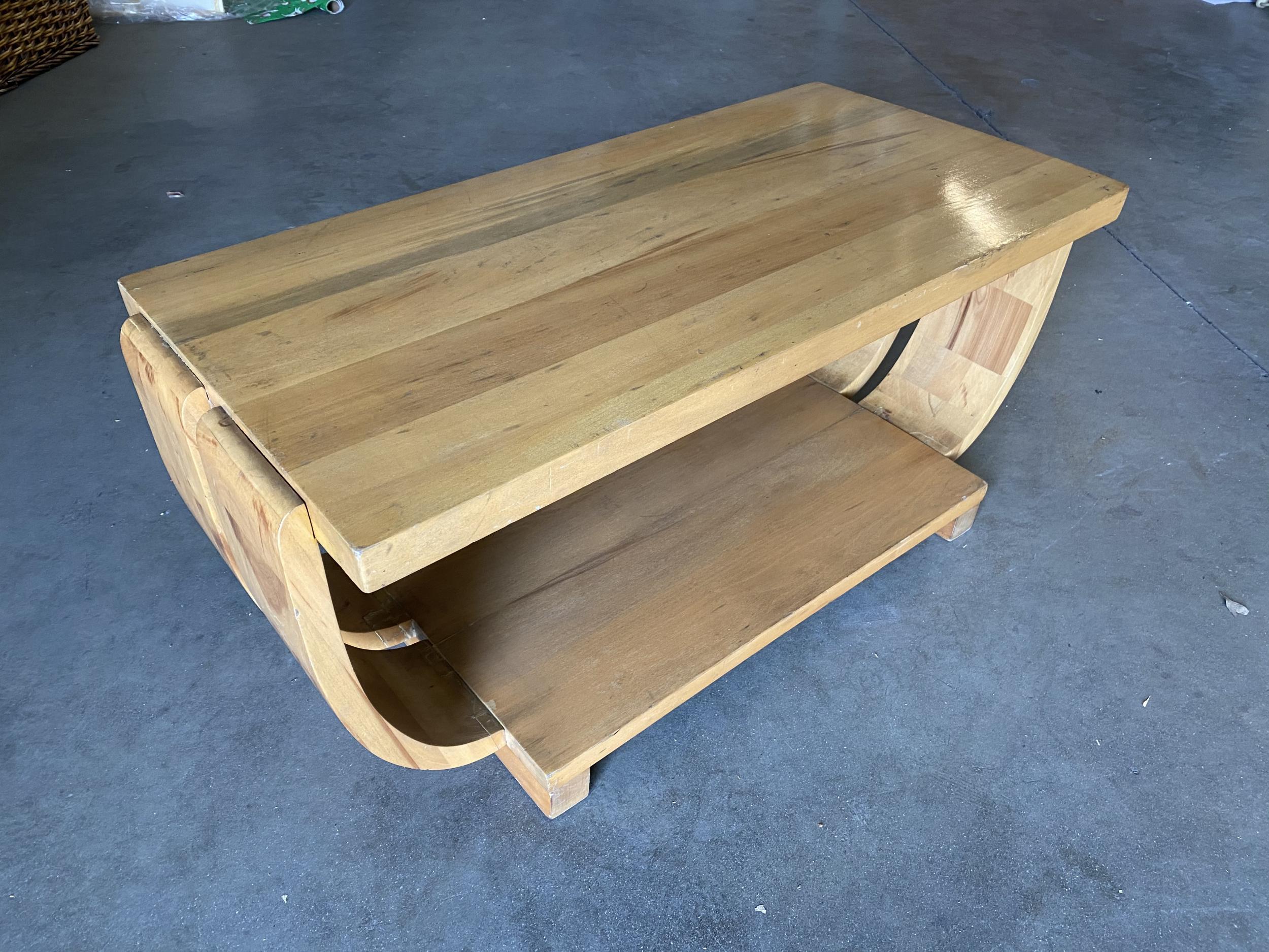 Beautiful streamline Brown-Saltman coffee table, circa 1930. The Classic Art Deco styling is accentuated by the table's natural stain mahogany panels which curve to connect the natural mahogany-finished top and base.