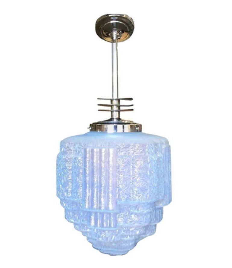 Raro colgante de techo Art Decó cromado con detalles aerodinámicos esmaltados en negro y globo de cristal Art Decó de textura azul.

La caída puede ser de 12