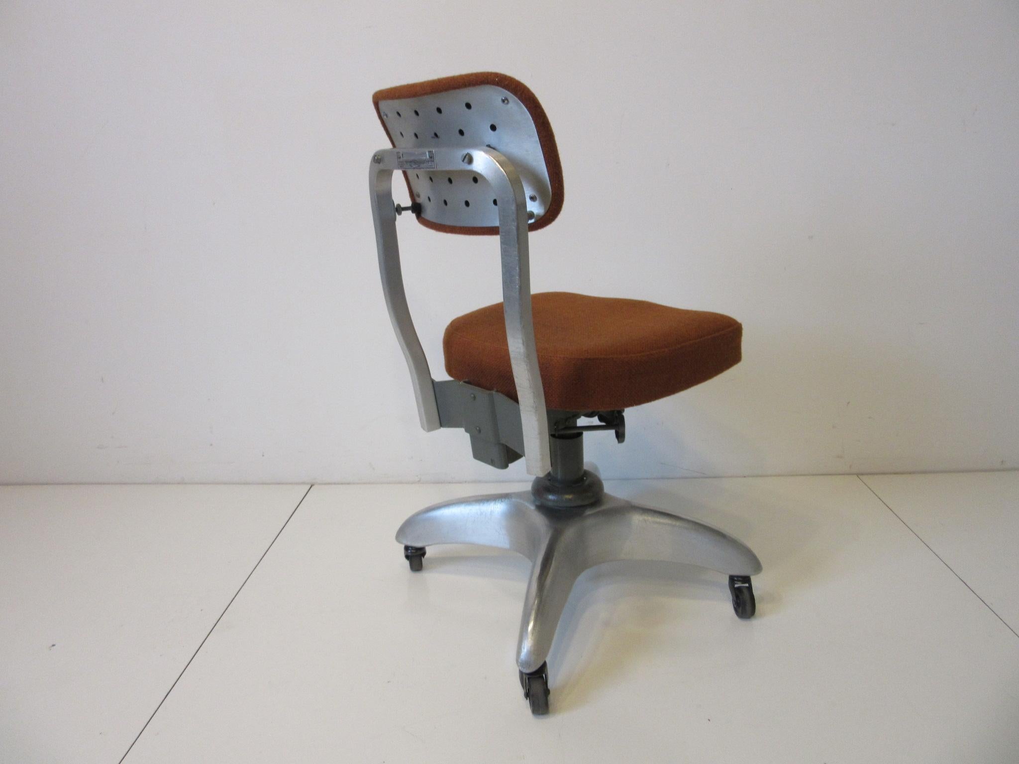 A streamline / industrial rolling, swiveling and adjustable desk chair with wonderful backrest design that also tilts for comfort. Cast aluminum star base and frame makes this chair light but very strong and long lasting upholstered in contract