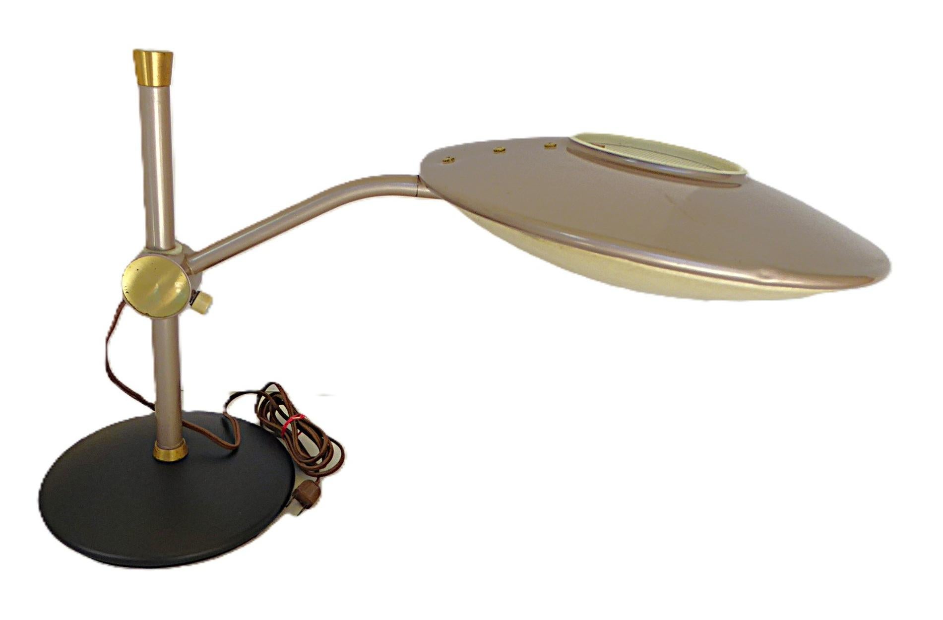  Dazor Lighting model #2008 Floating-Arm desk lamp.  It has a shade with a Flying Saucer shape with  a metal top and a fiberglass diffuser.  
From the Dazor website 