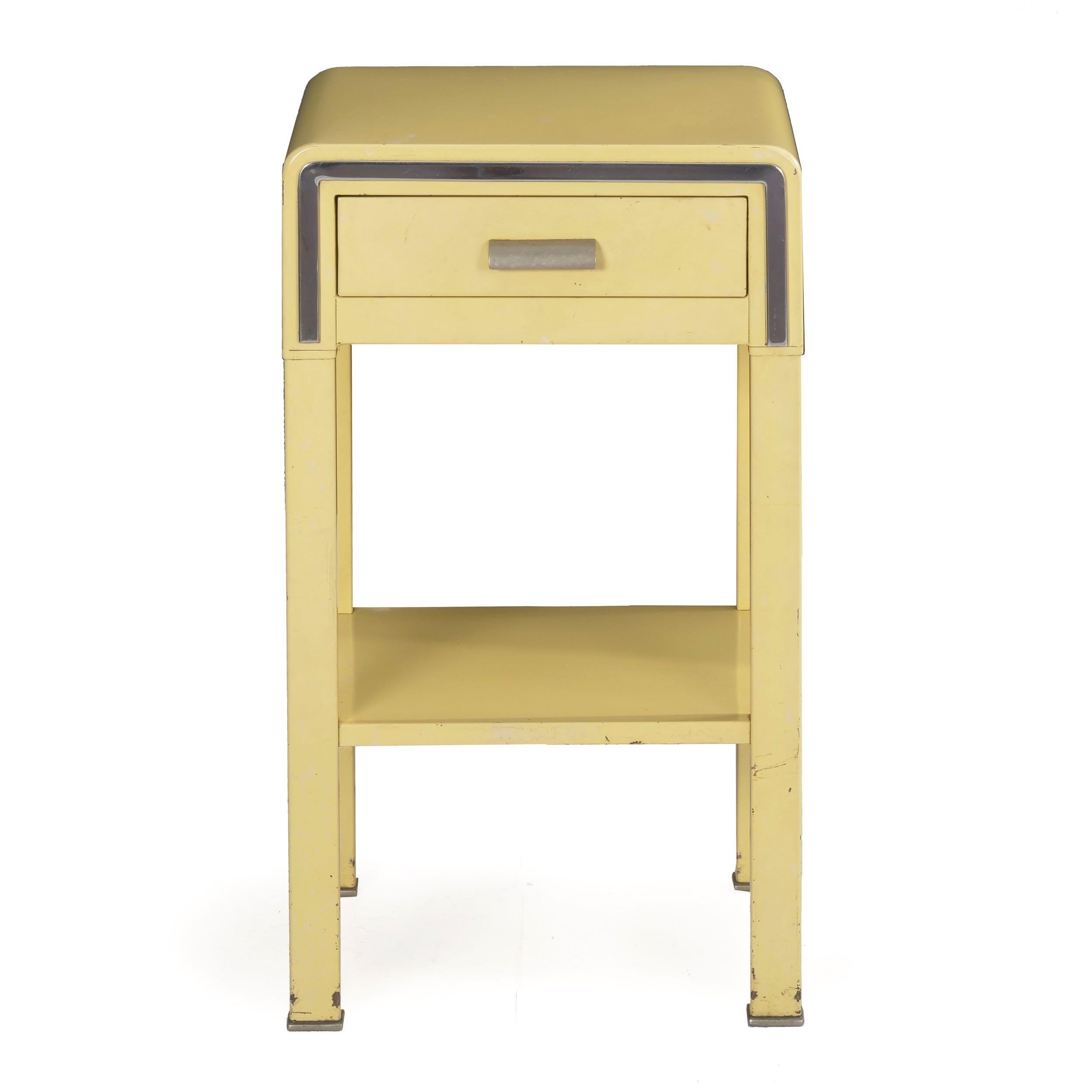 A rare original bedside nightstand table in yellow enameled steel designed by Norman Bel Geddes for Simmons in 1933, the small bedside table is characterized by extreme austerity with a pale yellow finish against chrome accents and a raw metal pull.