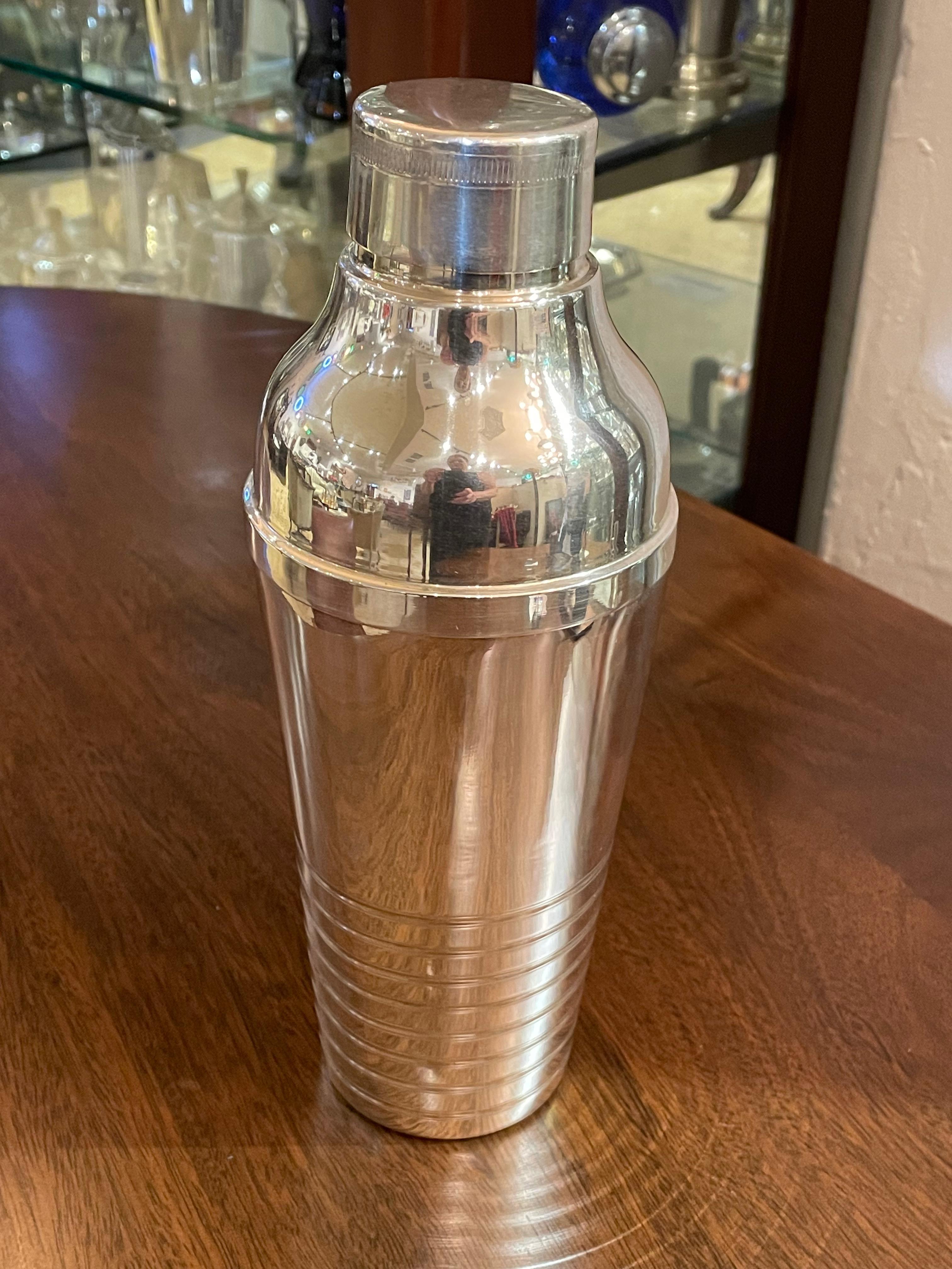Streamlined and classic French cocktail shaker that is silver plated and in perfect “gift-giving” condition with an interior as pristine as the outside design. This sleek shaker features the “speed line” detailing around the base- which also makes