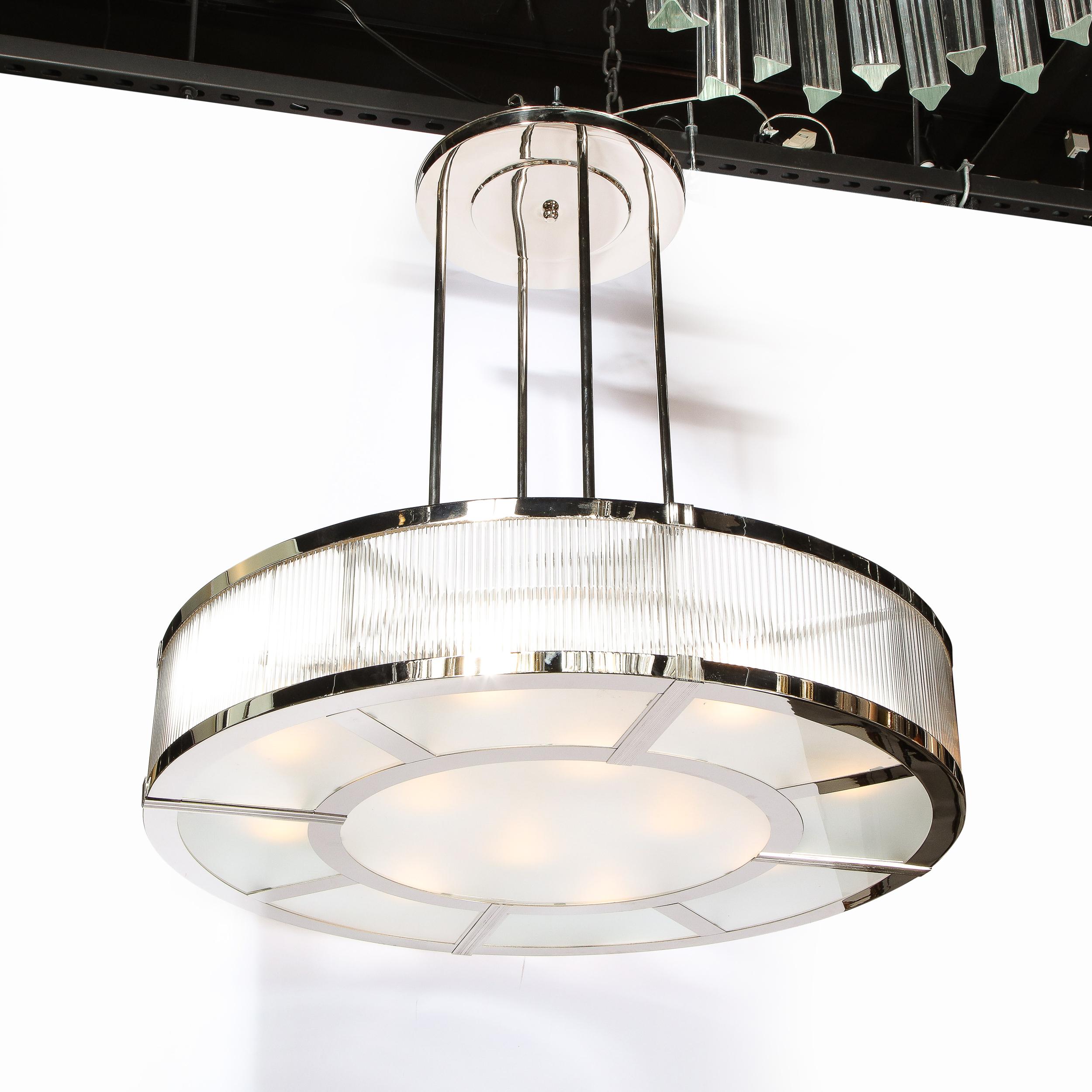 This large scale Machine Age French Art Deco style chandelier, in the manner of Petitot, features an abundance of vertically oriented glass rods supported by nickeled bronze fittings. On the bottom of the fixture frosted glass panels- a circular one