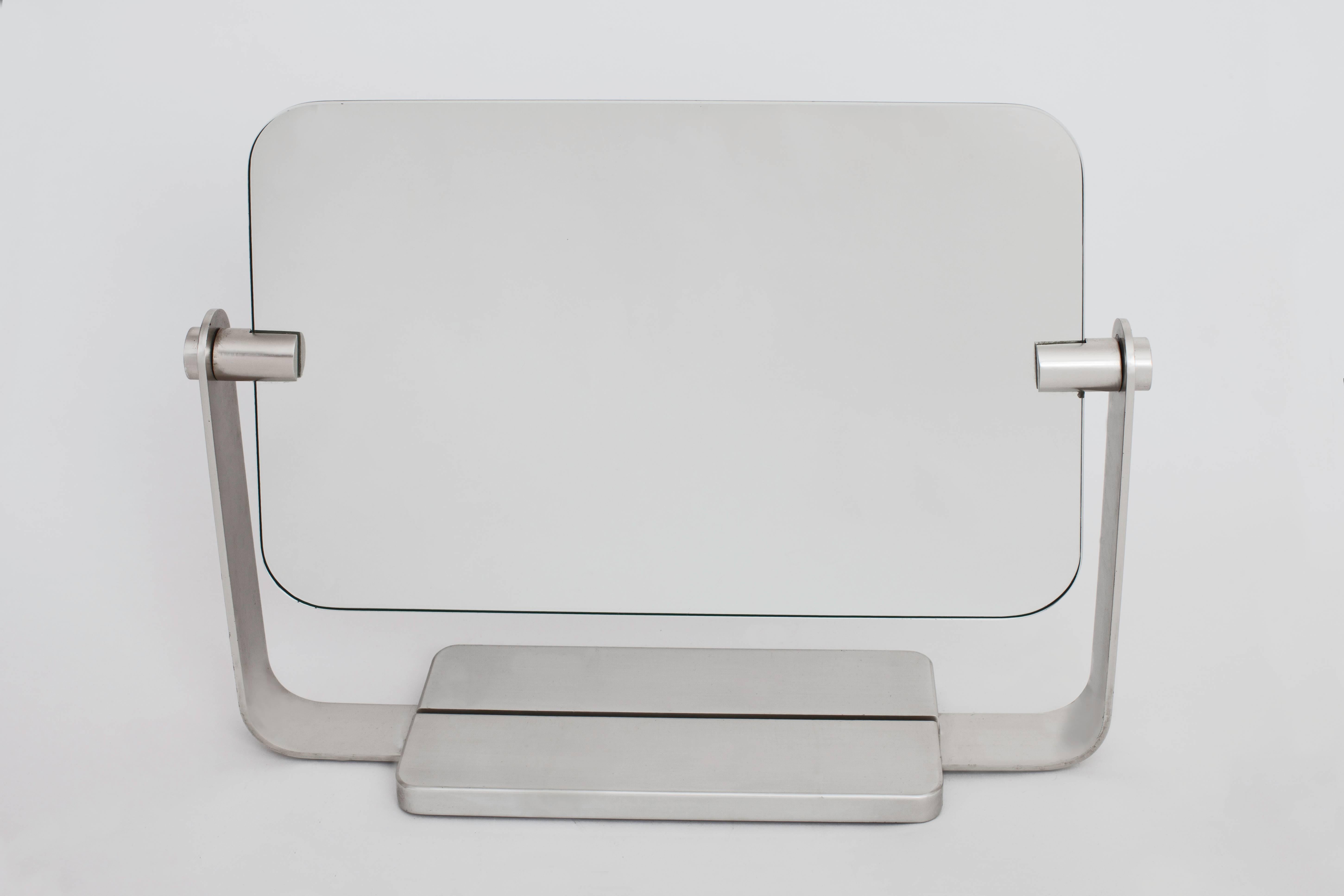 A graceful, fully rotating silver nickel vanity mirror with rounded corners and double-sided mirrored glass, one side colorless and the other tinted grey. With a bifurcated base and handsome, beautifully cast rectangular frame. Has been attributed