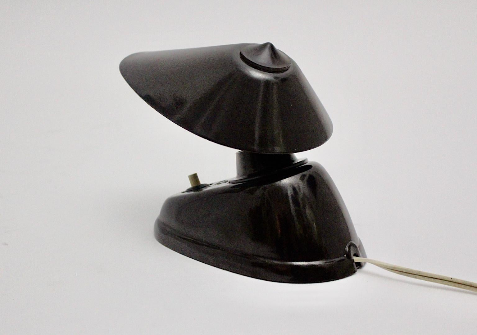 A streamlined Moderne Art Deco brown vintage Bakelite wall lamp or table lamp, which was designed and manufactured 1920s in Czechoslovakia.
The table lamp shows a base with one E 14 socket and an on/off switch, while the adjustable lamp shade