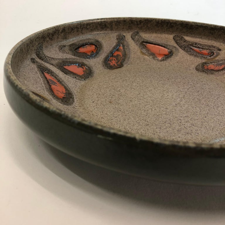 This beautiful ceramic bowl/dish with orange fat lava ovals, teardrop shape, East-Germany.
The dish is from former East Germany marked at the bottom.
Dimensions: 5 x 25 cm.

 