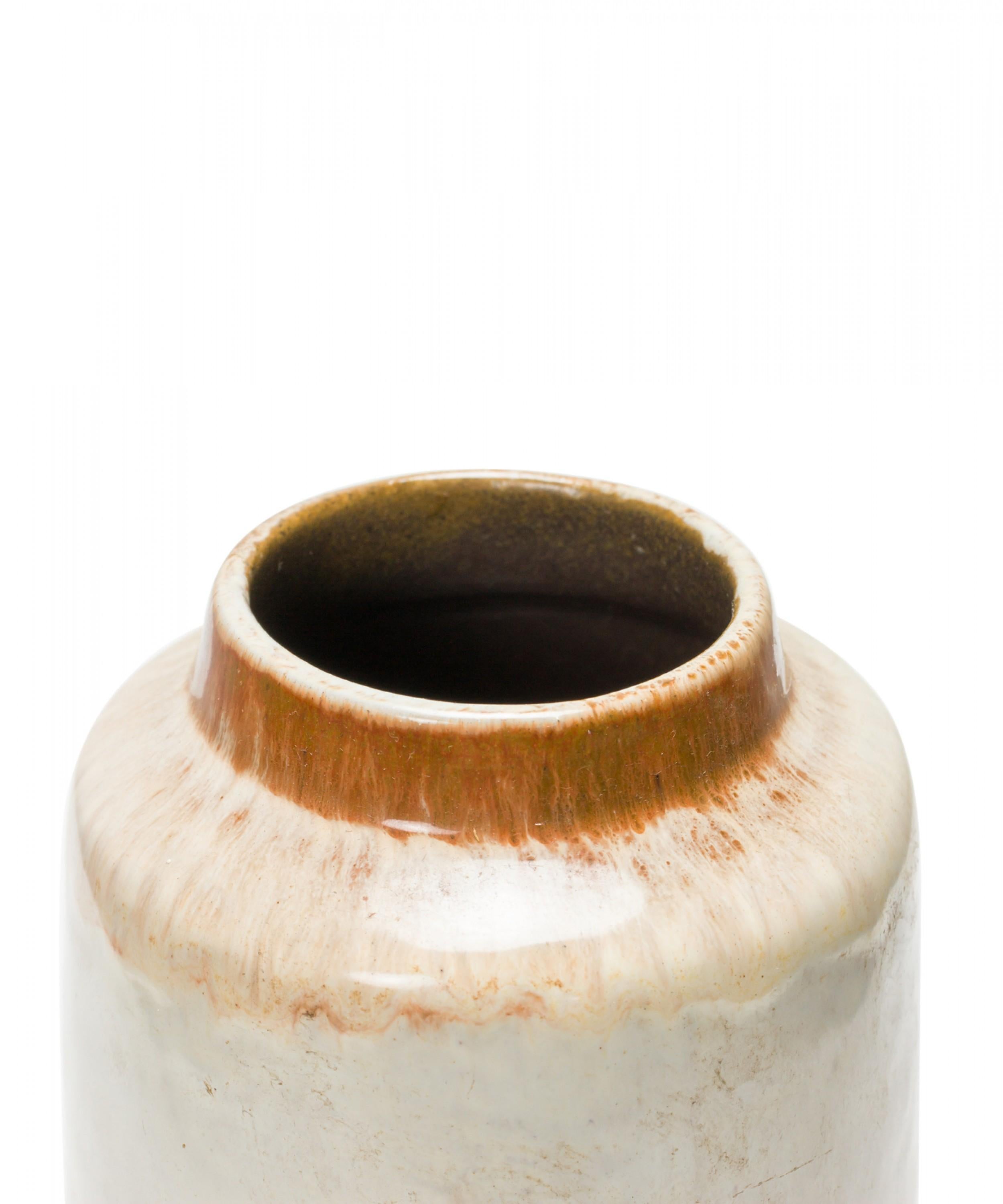 Vaso cilindrico in ceramica della Germania dell'Est della metà del secolo scorso con smalto di base beige e una fascia decorativa centrale con forme floreali astratte dai contorni in rilievo in rosso e marrone. (STREHLA KERAMIK, marchio sul fondo).