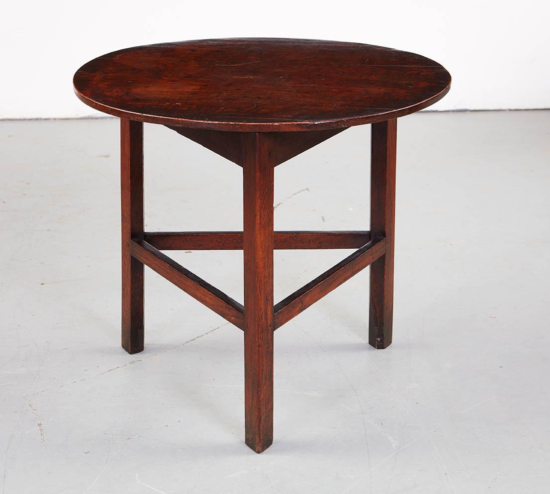 An 18th century cricket table in oak with a round top over three legs joined by stretchers, retaining wonderful original dark surface and have a refined yet rustic feel. Three-legged cricket tables were developed to allow tables to stand without