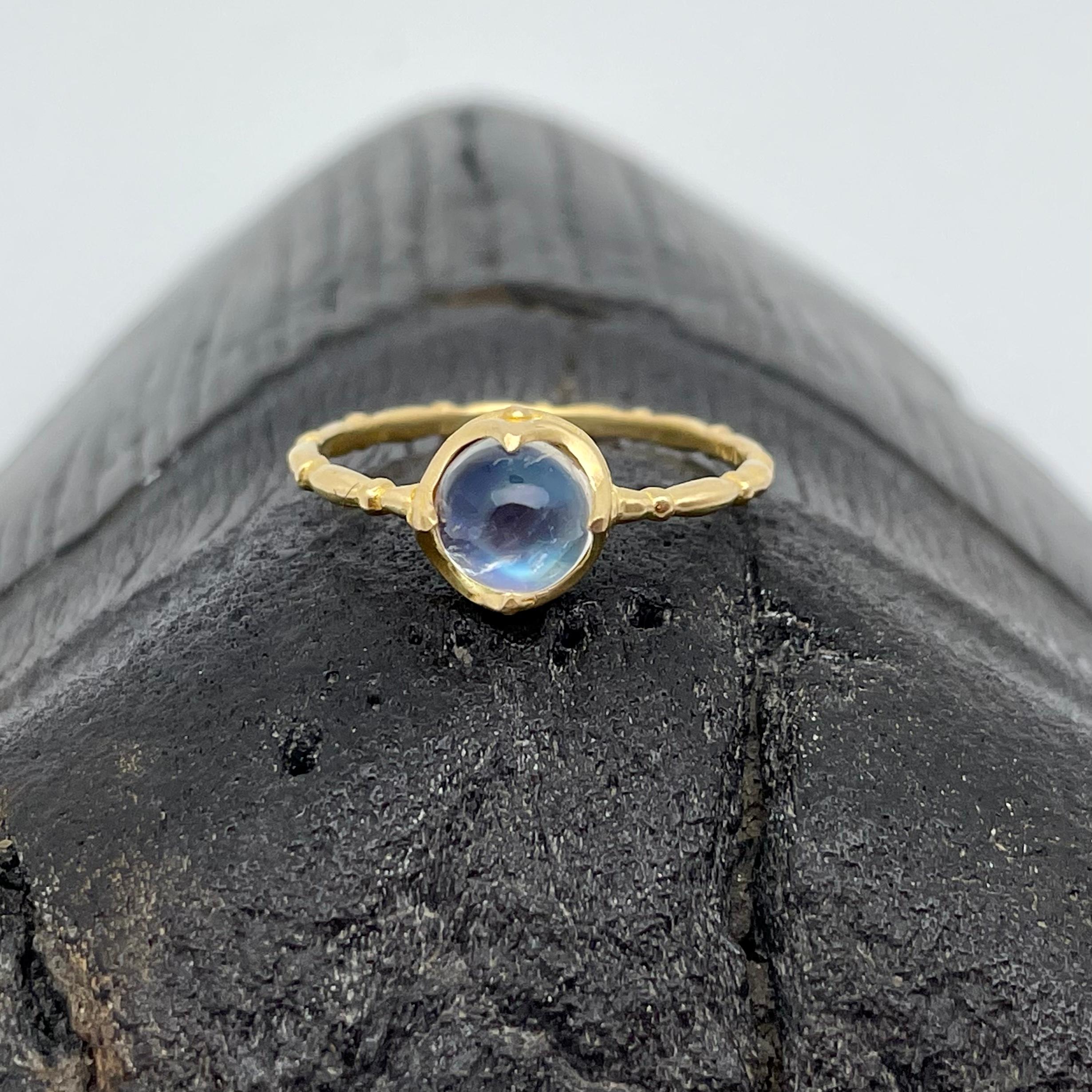 A top grade 6 mm round rainbow moonstone is held in an ancient-inspired 