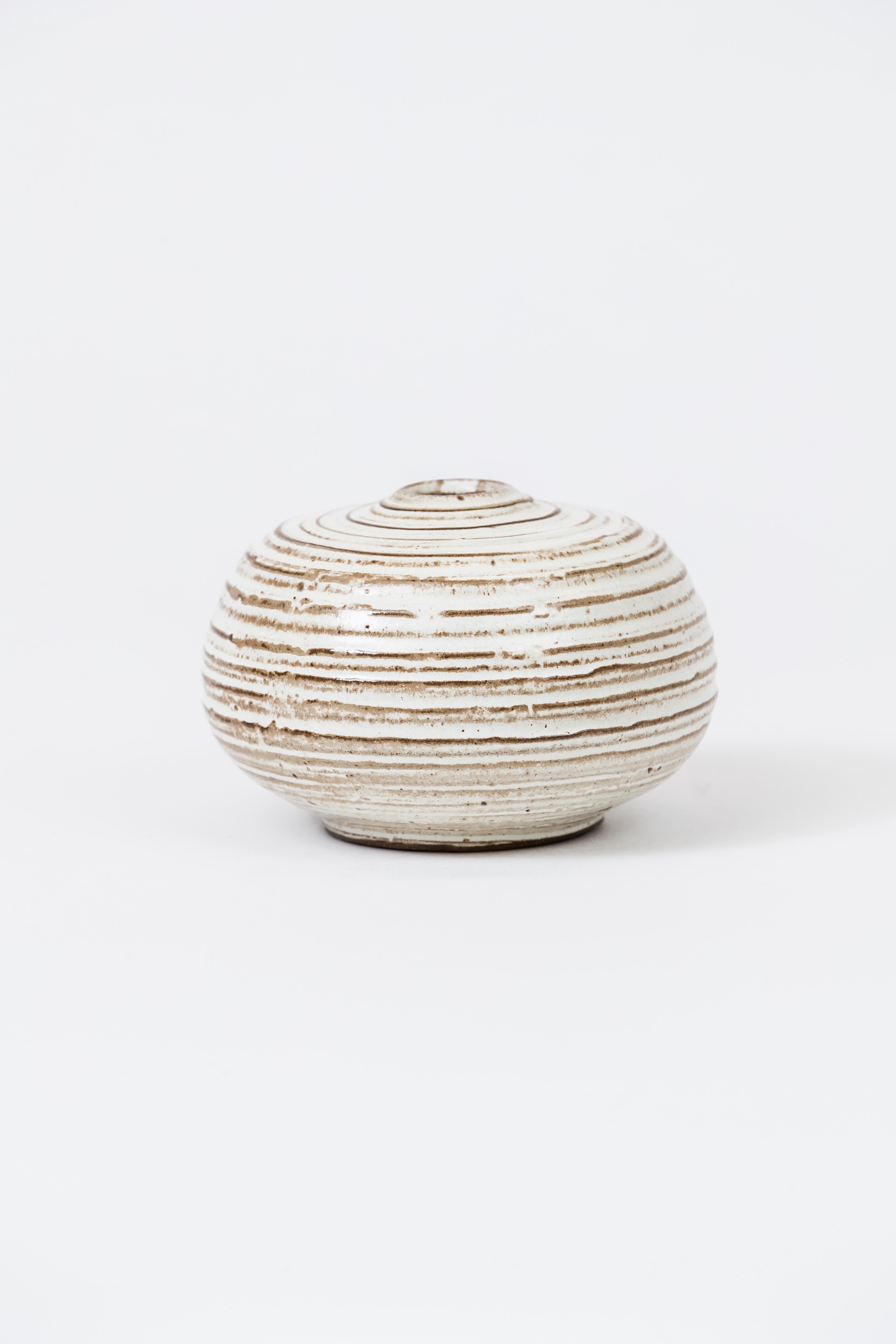 A striated ceramic bud vase in glazes of whites with earth tones reliefs.