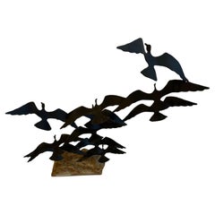 Scultura brutalista con uccelli in volo