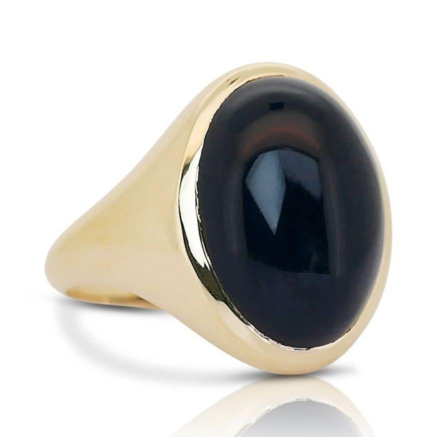Immerse yourself in the captivating allure of our striking 10.88 carat oval cabochon cut onyx ring, a masterpiece of timeless sophistication. Crafted with meticulous attention to detail, this exquisite ring boasts a lustrous 18K yellow gold setting